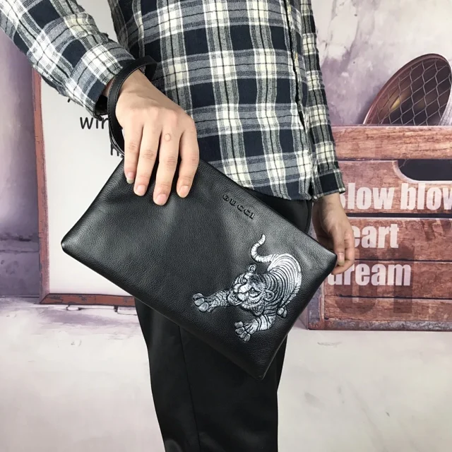 Gucci black leather clutch bag with a tiger design.