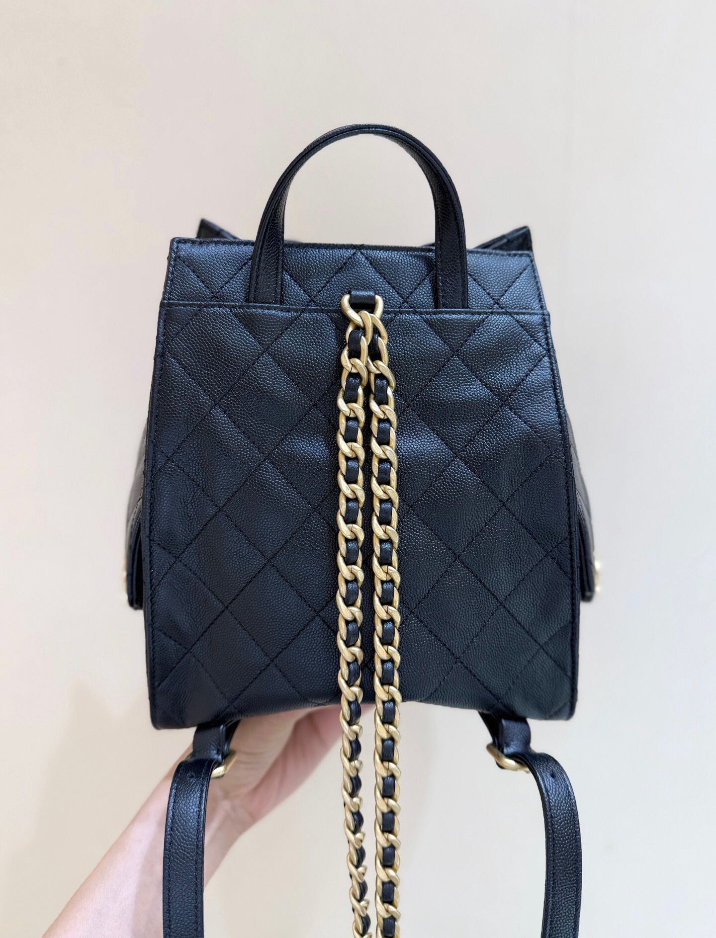 Chanel 25 medium backpack in black grained calfskin and gold-tone metal.