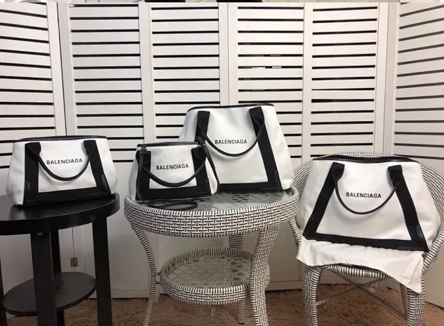 Balenciaga Navy Cabas XS tote bag in a two-tone white canvas body with black leather trim and a logo print on the front.