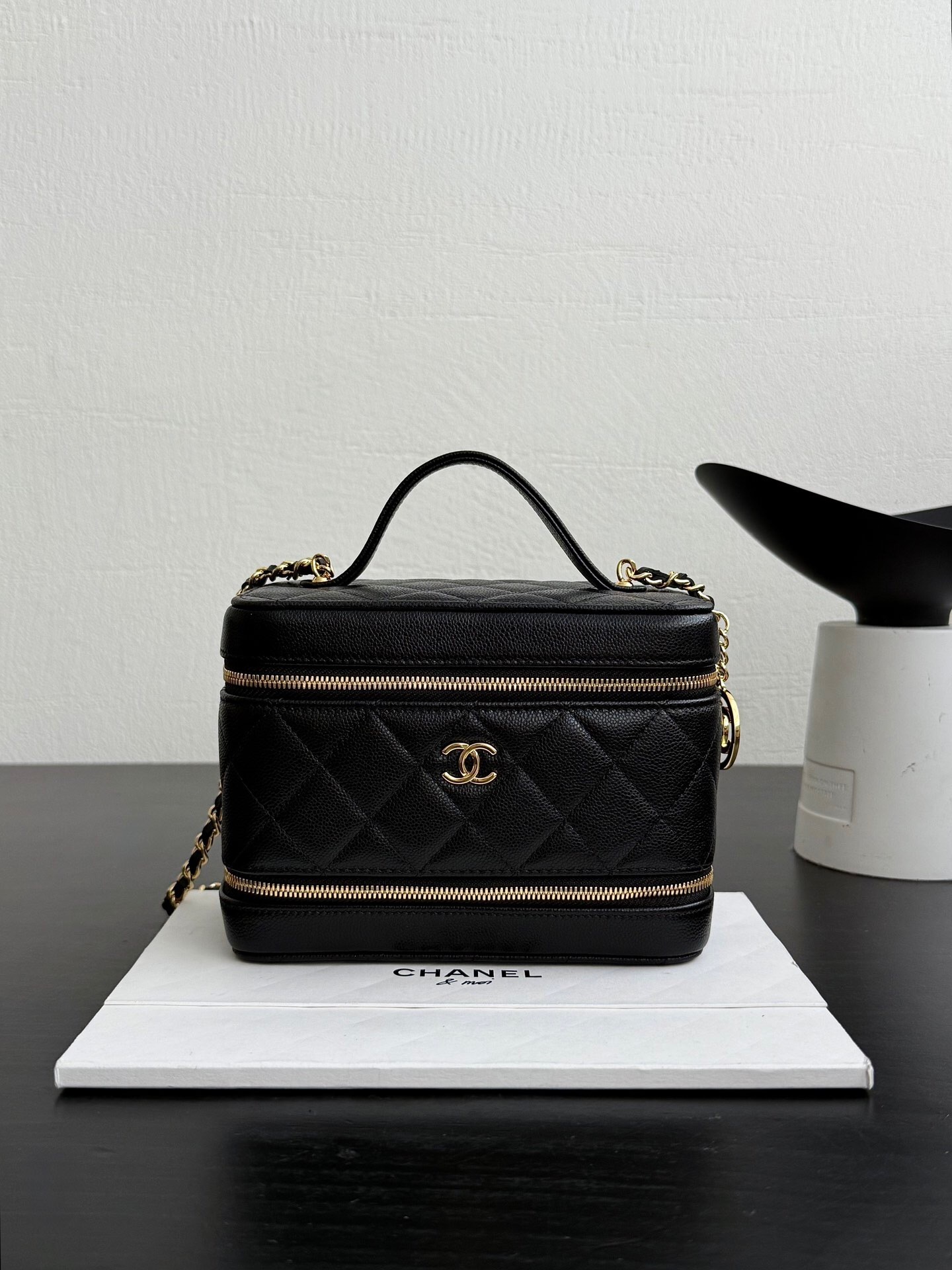 Chanel Vanity Case with a top handle black leather with gold-toned hardware.