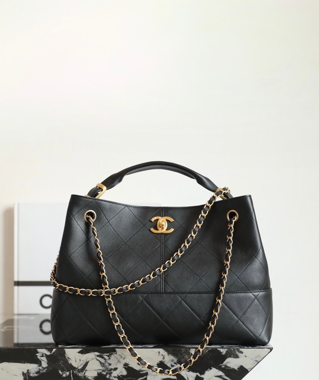 Chanel bucket bag black with a quilted pattern and a gold chain strap.