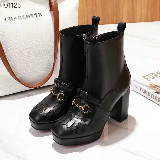 Gucci black leather ankle boots with a platform sole, block heel, and a gold-tone horsebit detail.