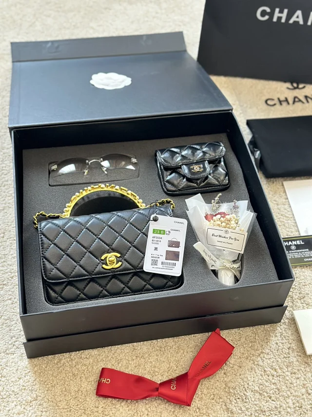 Chanel handbag with a top handle, a quilted pattern, and a chain-link strap black