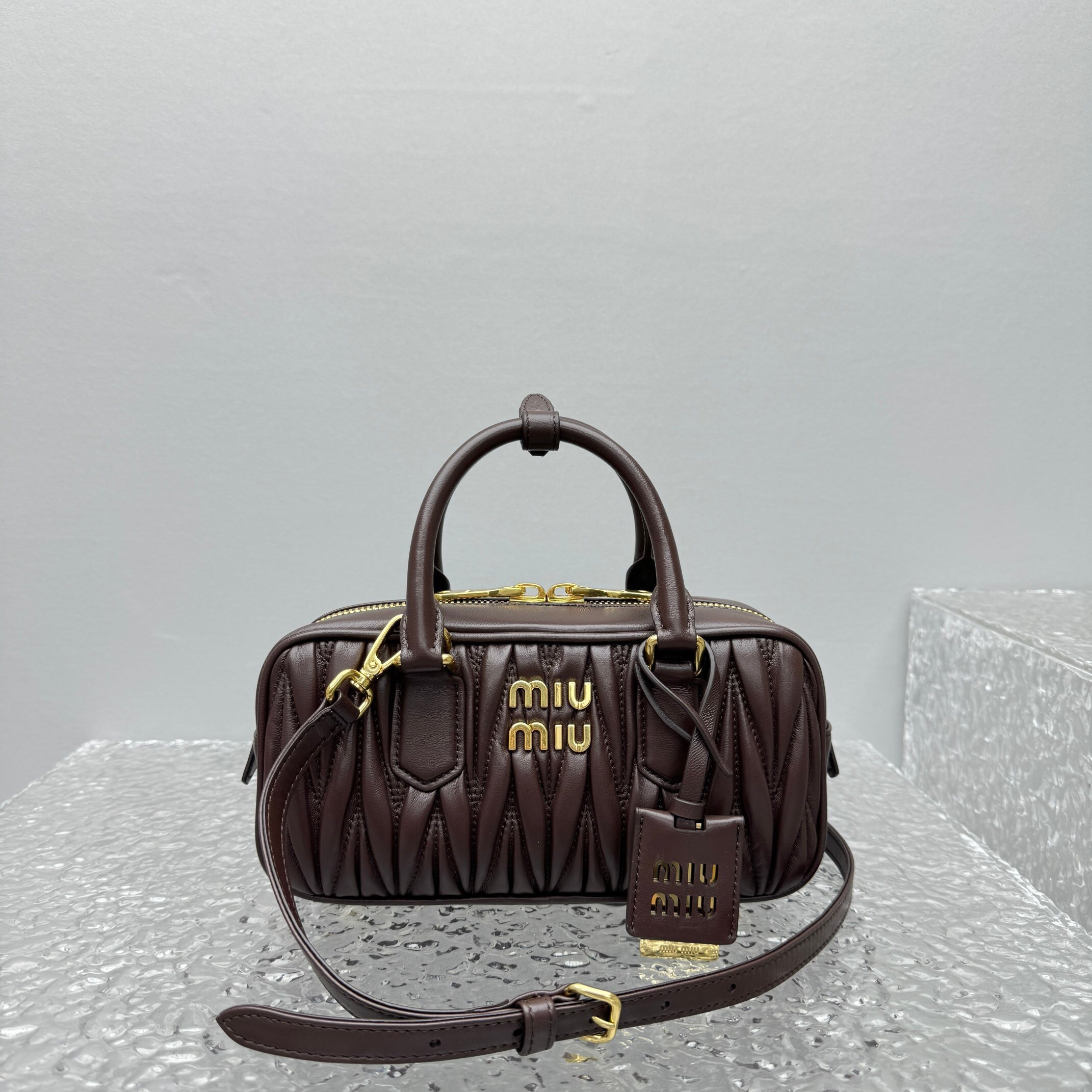 Miu Miu Arcadie matelassé leather top handle bag in a dark brown or bordeaux color.