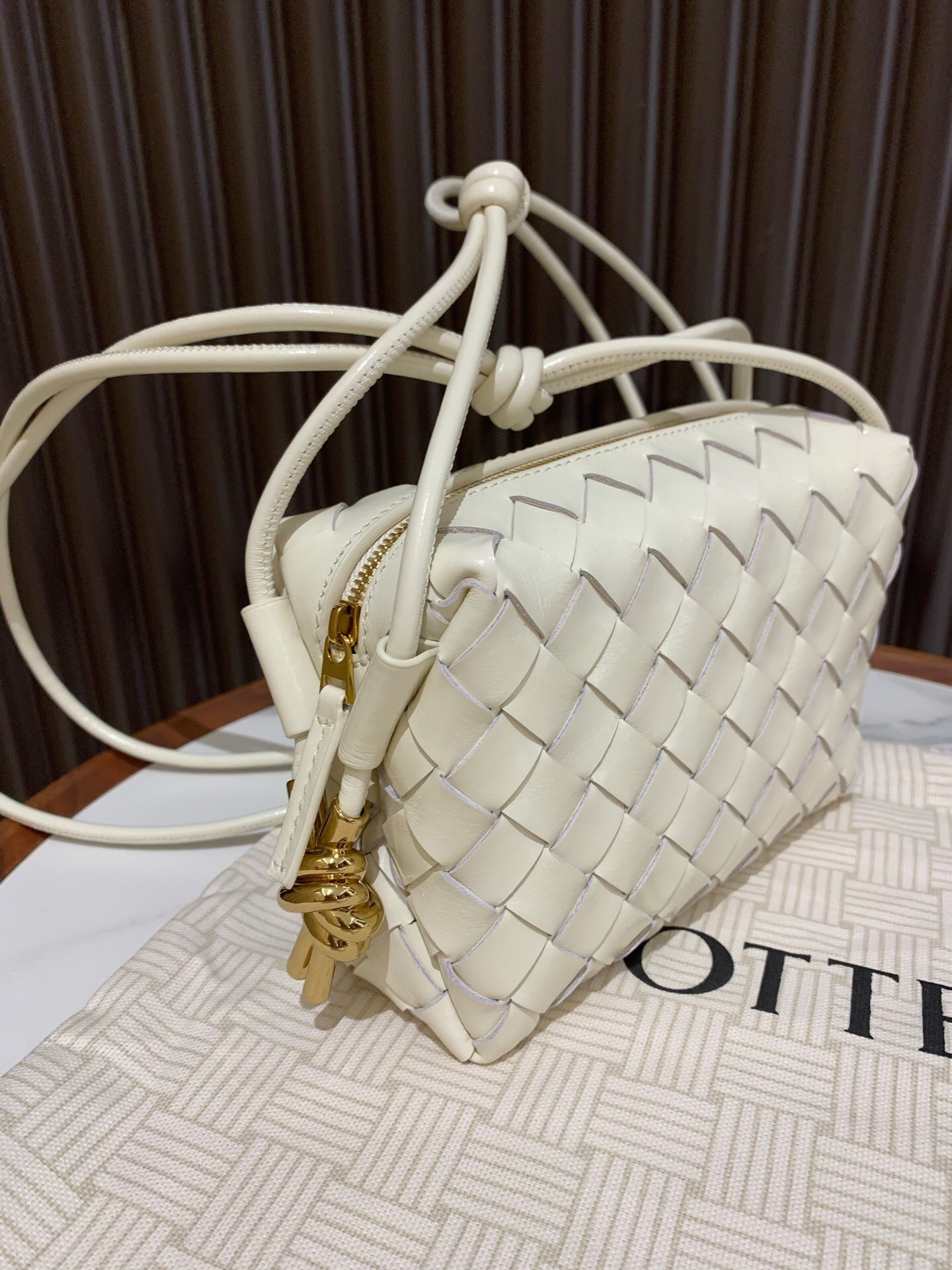 Bottega Veneta Mini Loop Metal Knots crossbody bag in bone-colored lambskin leather with a muse brass finish on the hardware
