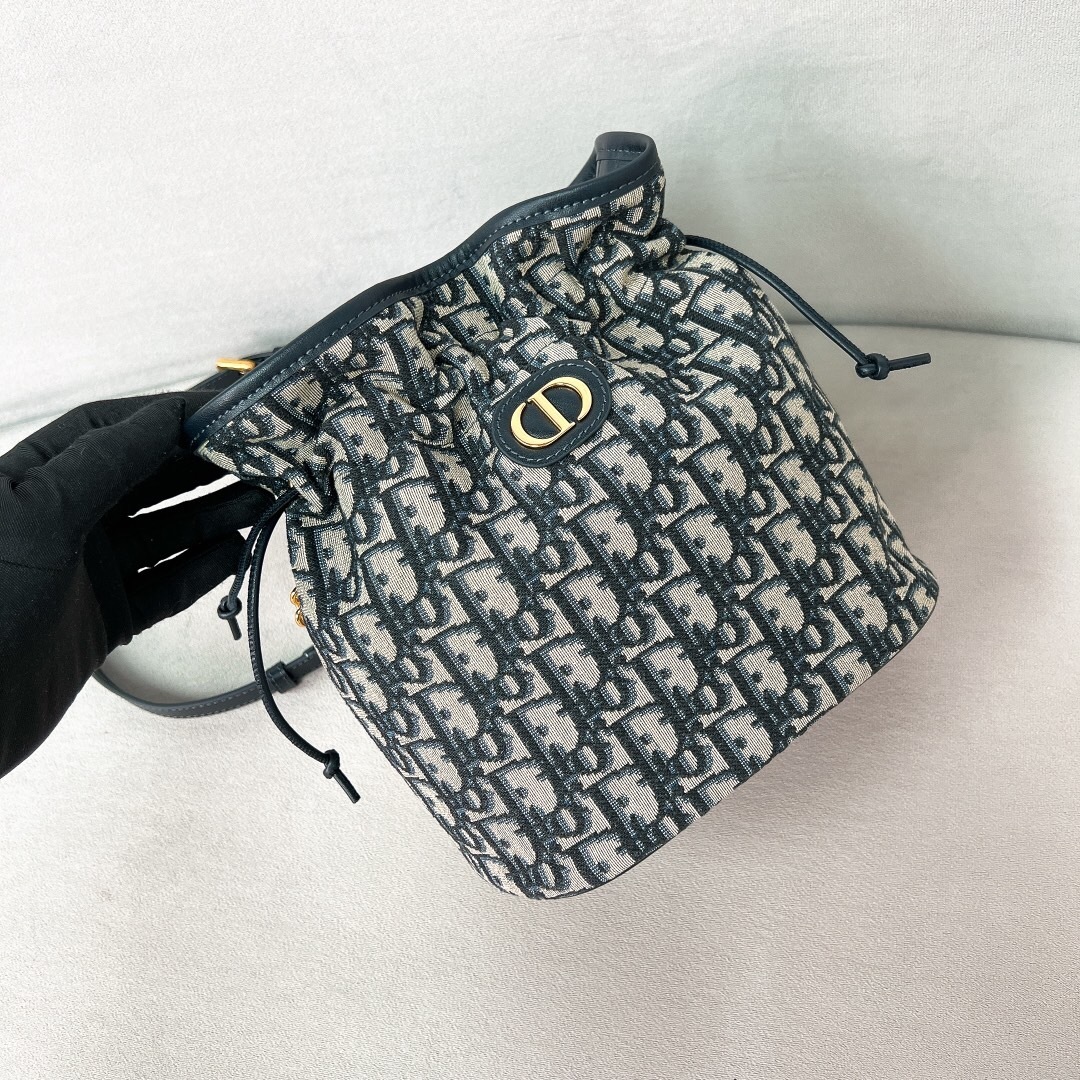 Dior 30 Montaigne drawstring mini bucket bag in blue Dior Oblique jacquard canvas with an antique gold-finish metal "CD" signature on the front