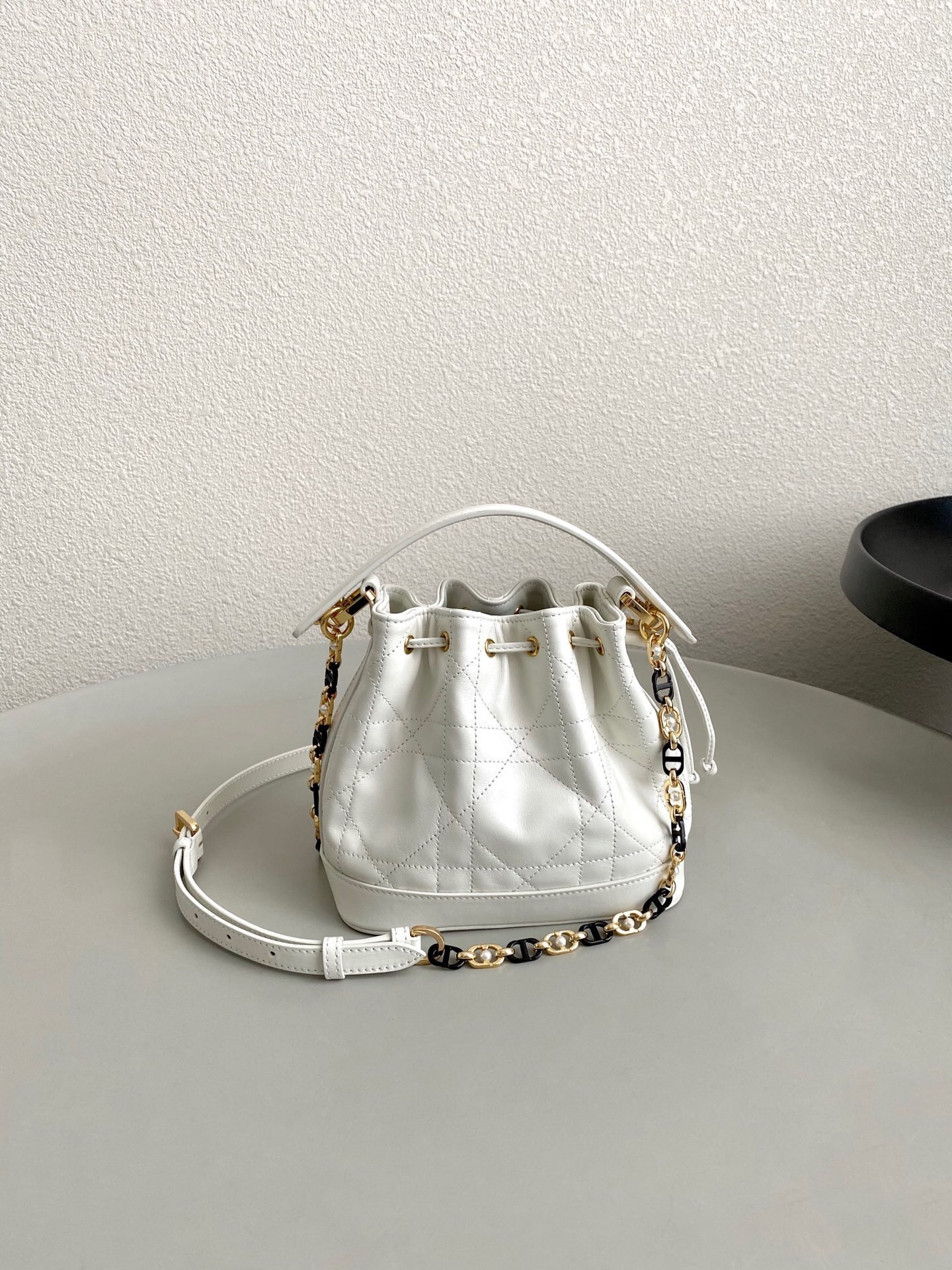 Dior Small Jolie bucket bag in white (or similar off-white shade) with caning stitching and a gold-finish metal CD link chain accented by resin pearls