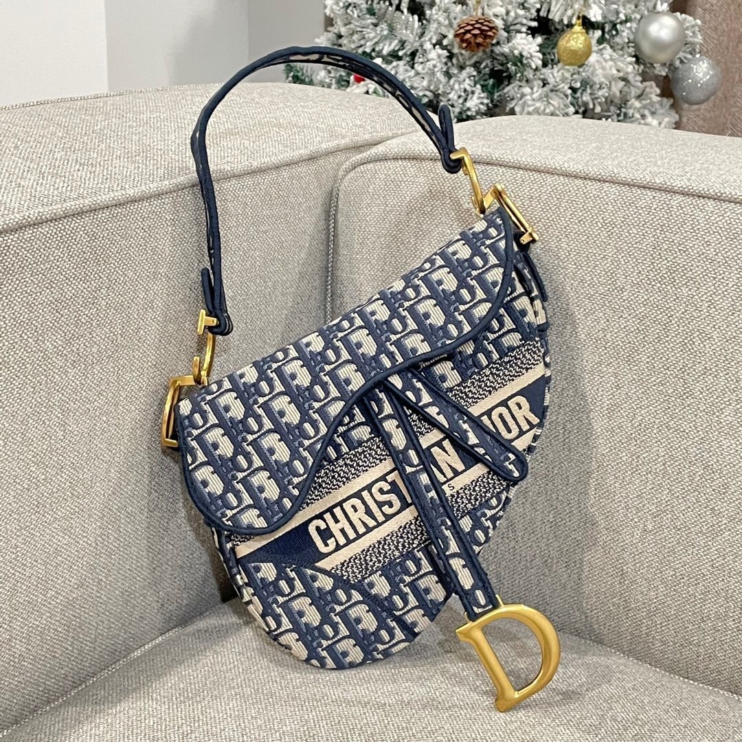 Dior Saddle Bag in blue Dior Oblique embroidery with a "Christian Dior" embroidered shoulder strap.