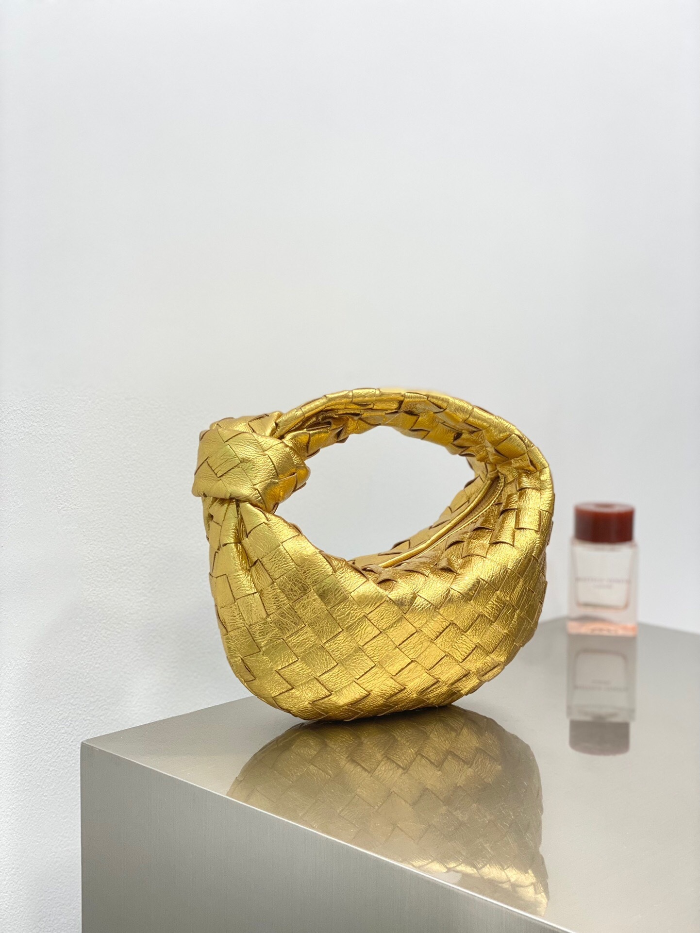 Bottega Veneta Mini Jodie bag in gold-toned leather with the signature Intrecciato weave and knotted handle