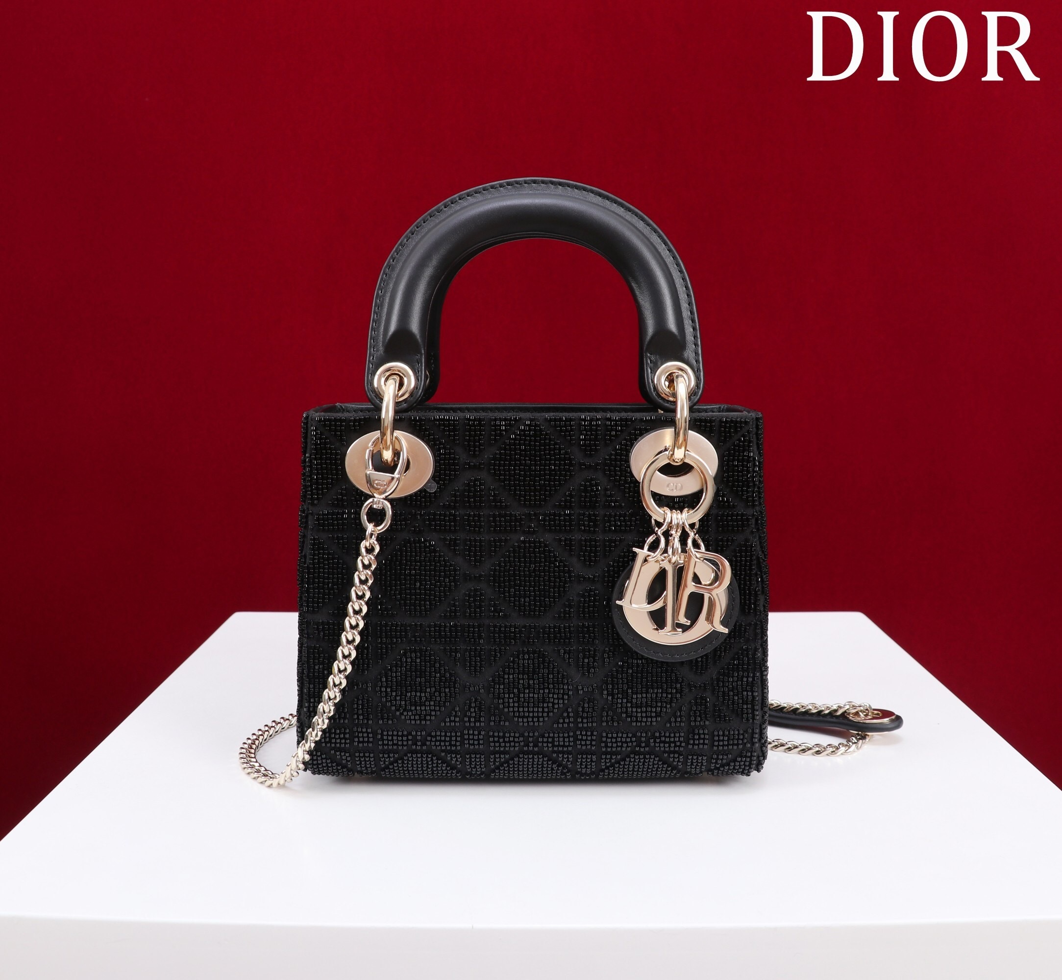 Christian Dior Lady Dior bag in black satin with gold-tone hardware and D.I.O.R. charms.