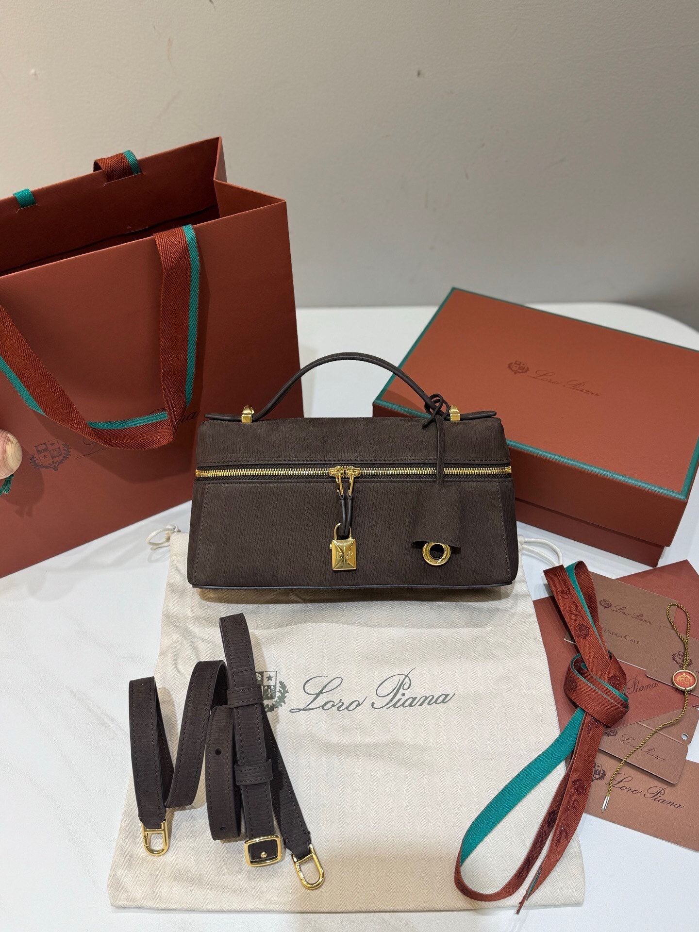 Loro Piana Extra Bag L23 in dark chocolate licorice suede or calfskin, featuring sun gold-tone hardware and signature lock charms
