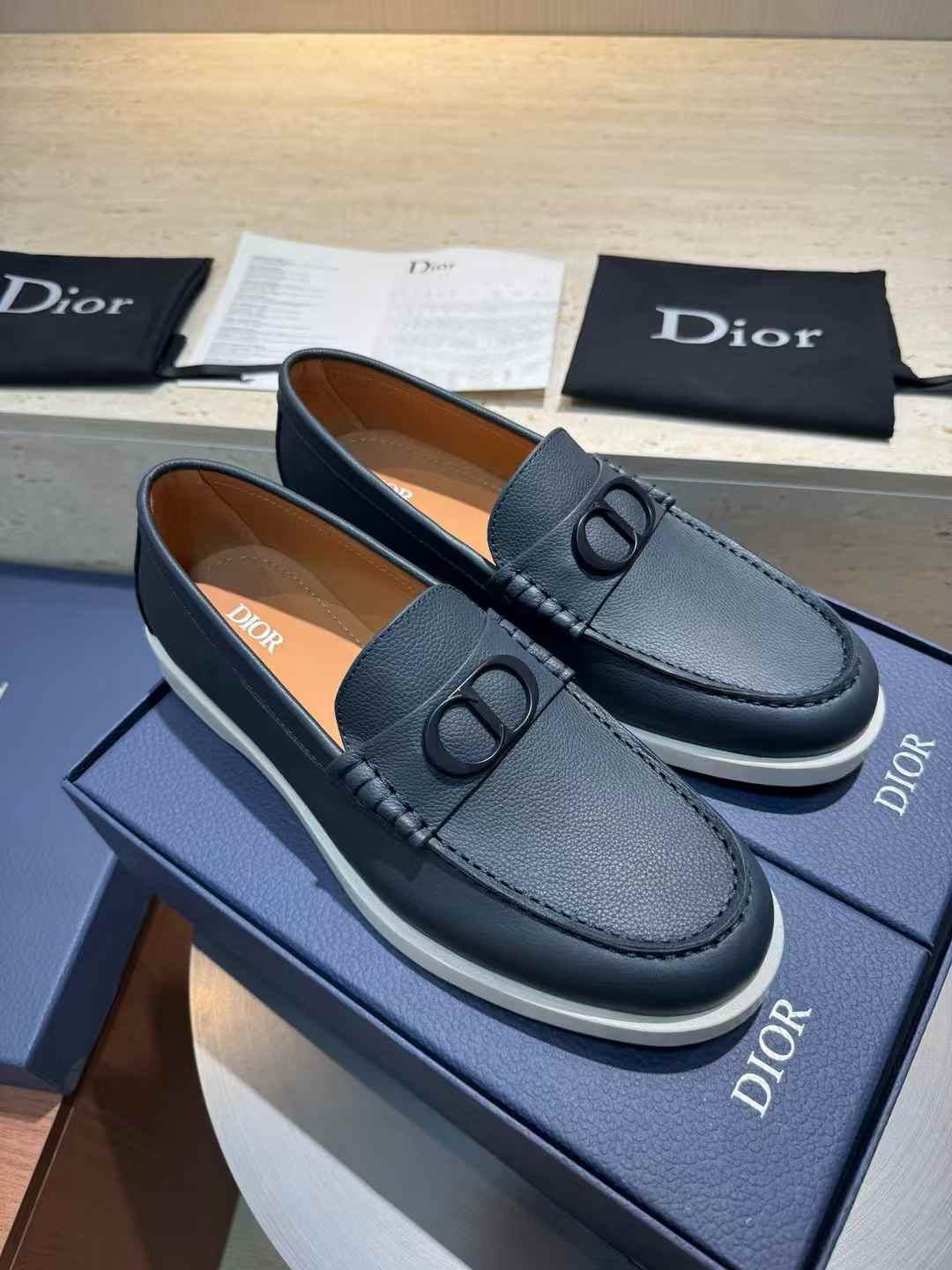 Dior Granville loafers in black polished calfskin with a white rubber sole and a palladium-finish brass "CD Icon" buckle on the vamp