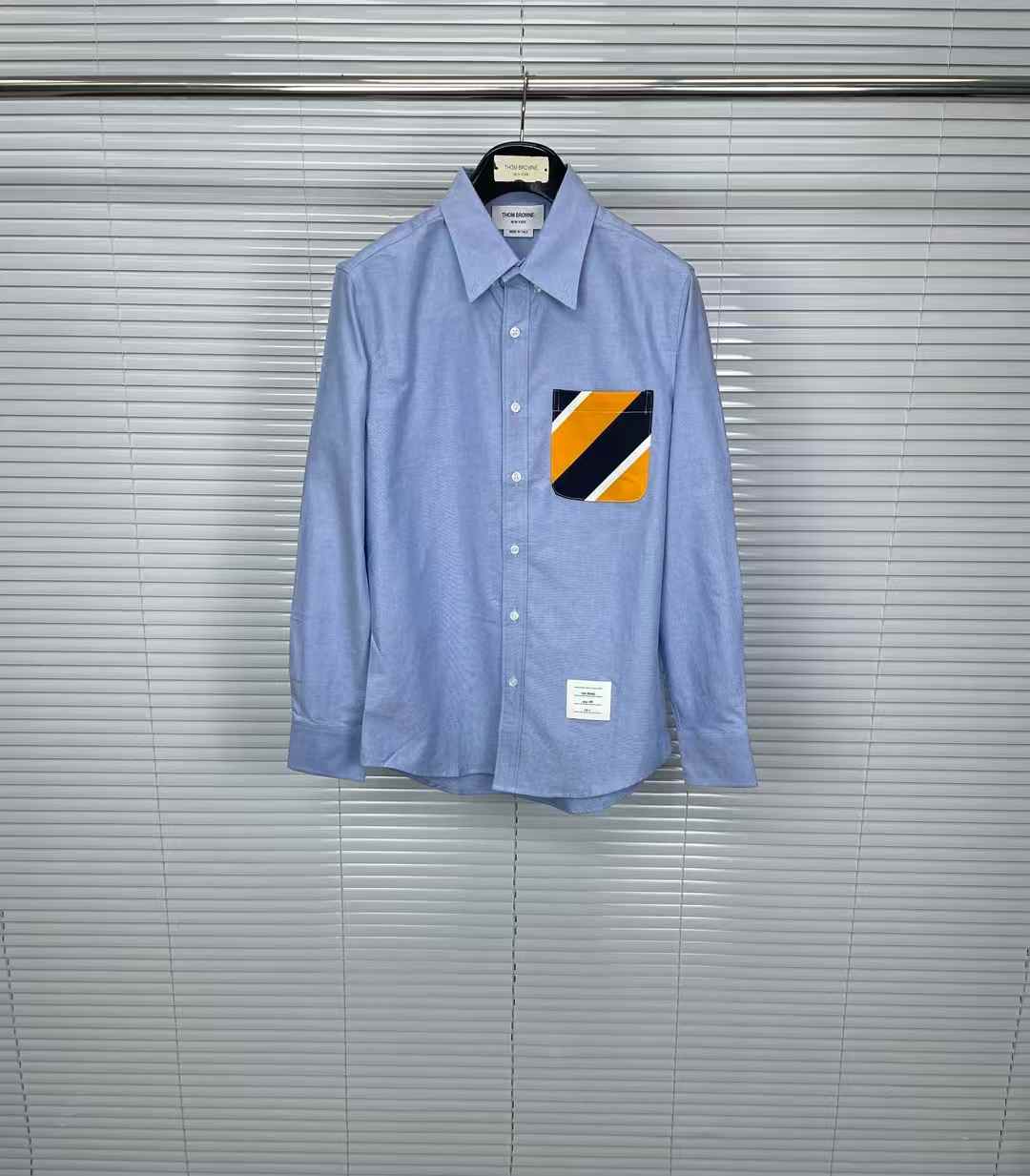 Thom Browne light blue long sleeve button-up shirt with an orange and navy striped pocket