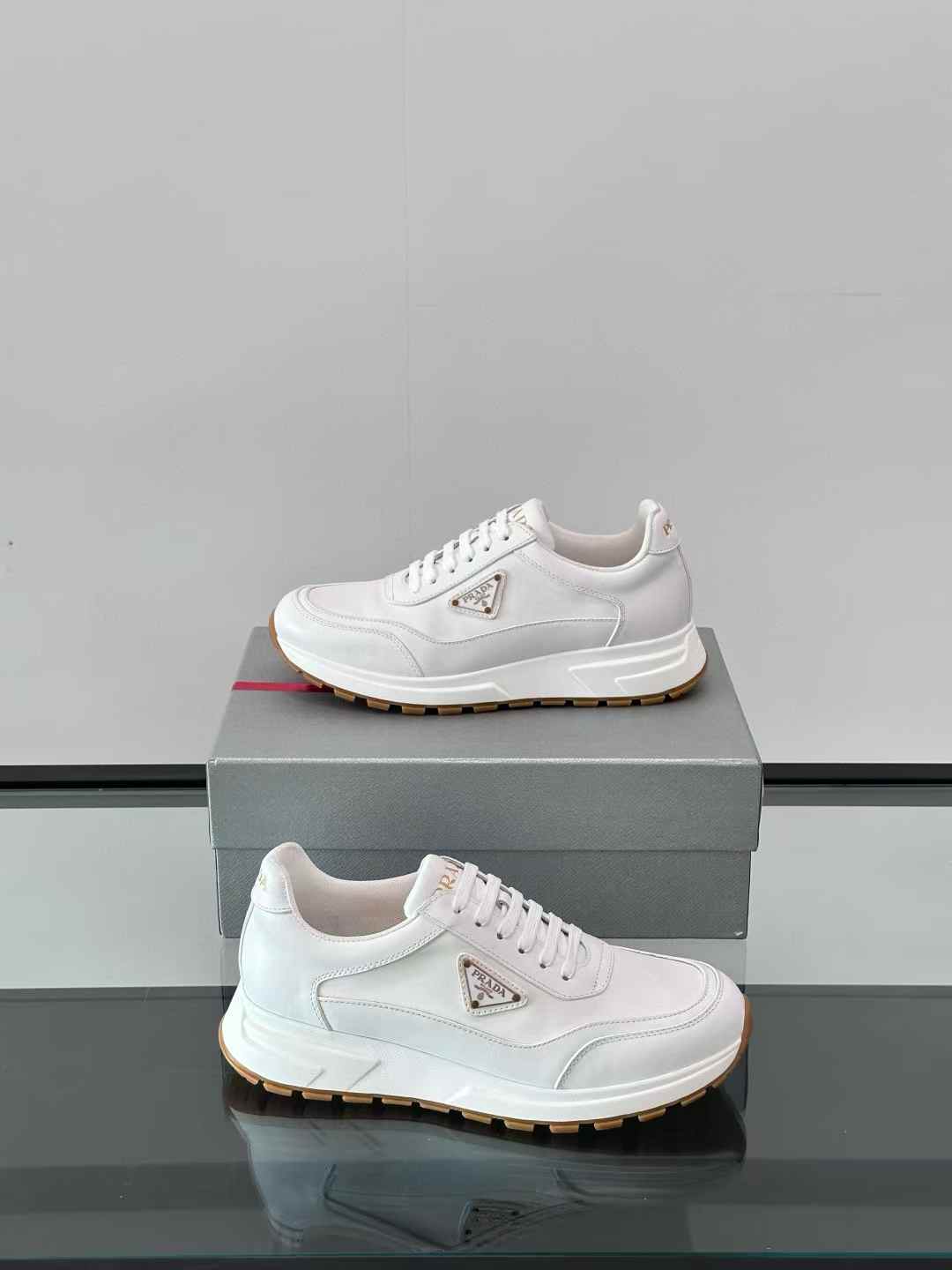 Prada white leather sneakers with a front lace-up fastening and an enamel triangle logo