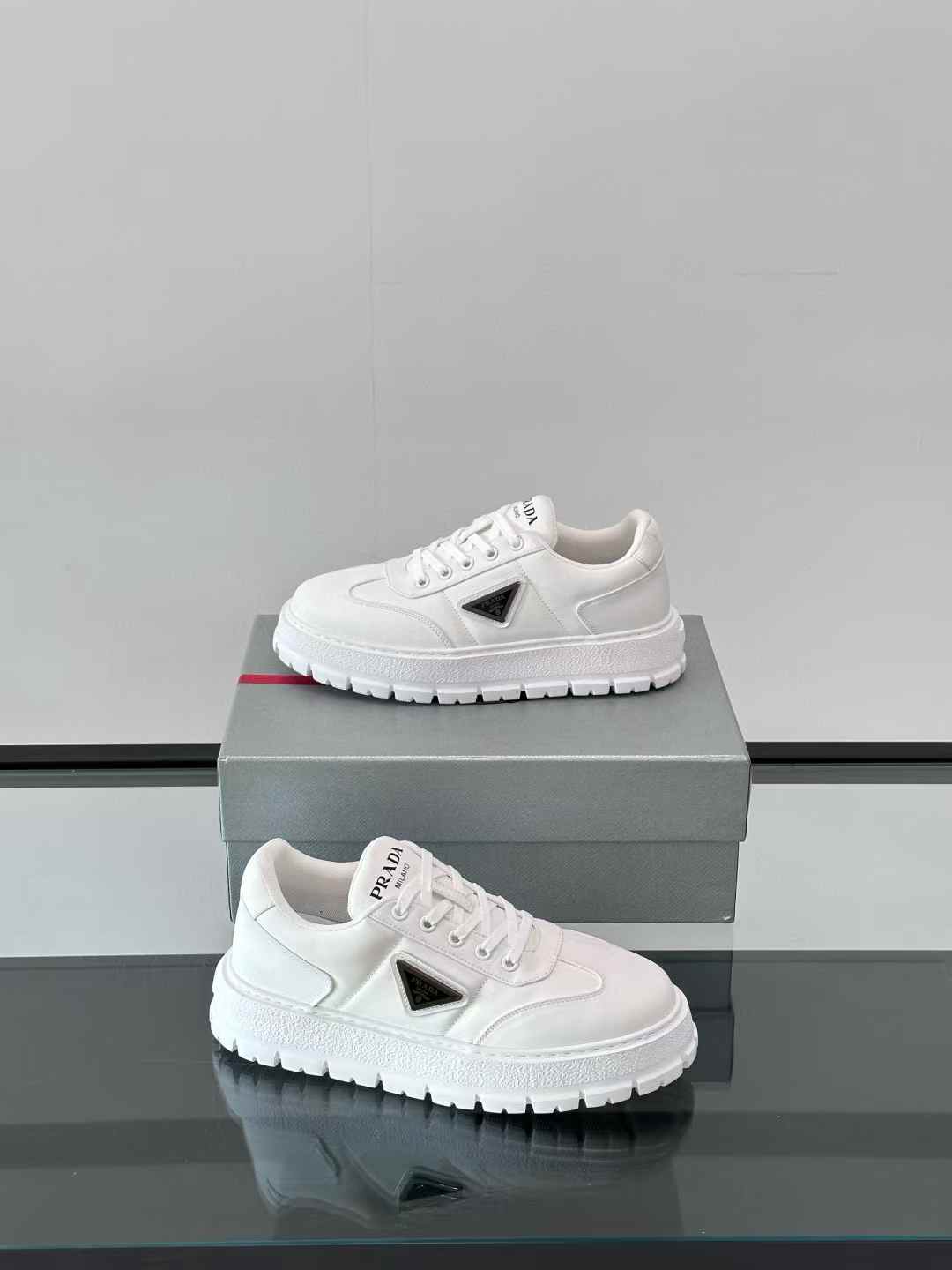 Prada white sneakers with a black triangular logo and a chunky sole