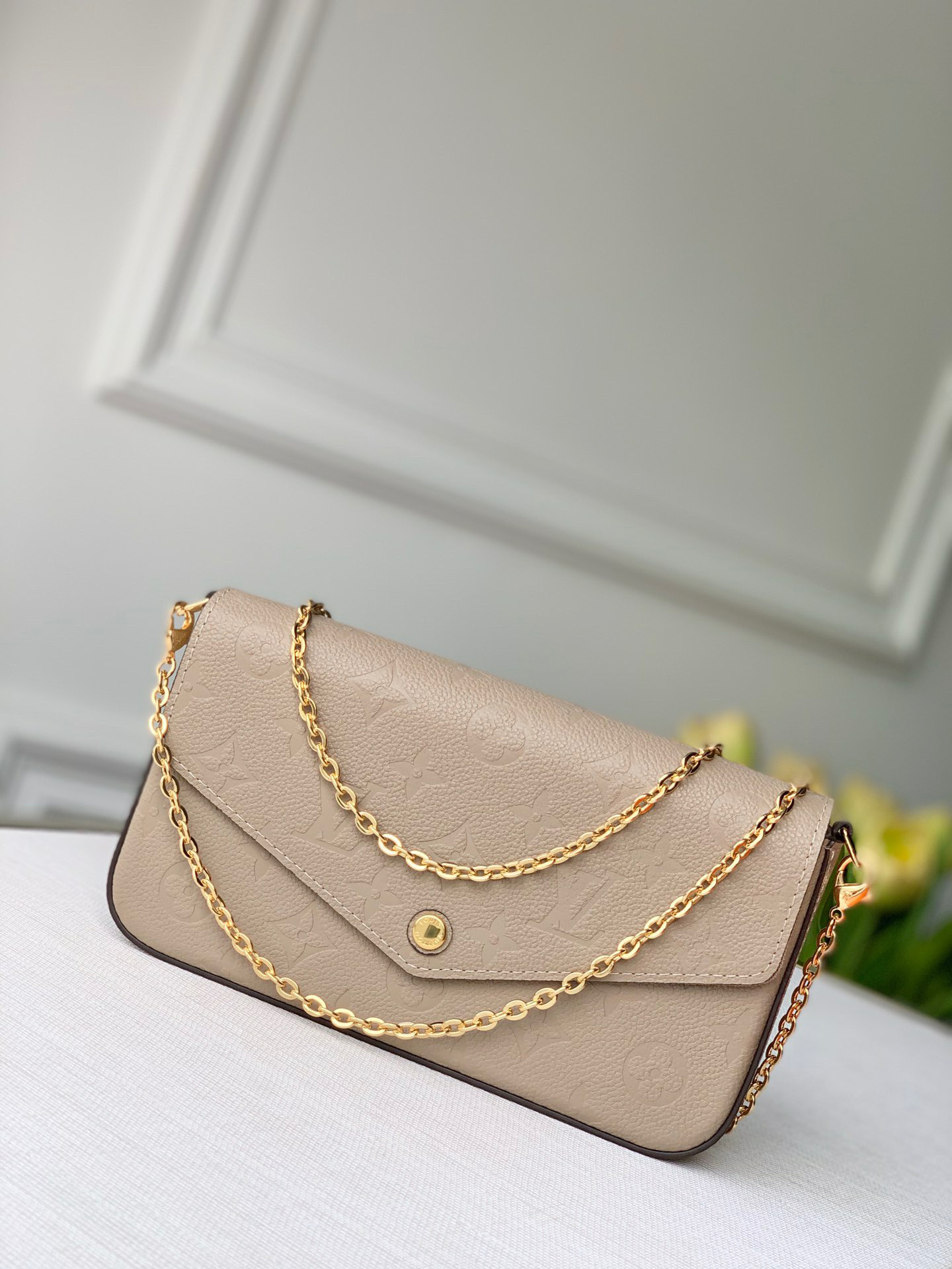 Pochette Félicie bag in Monogram Empreinte leather, likely the "Tourterelle" or "Dune" color with a gold-tone chain.