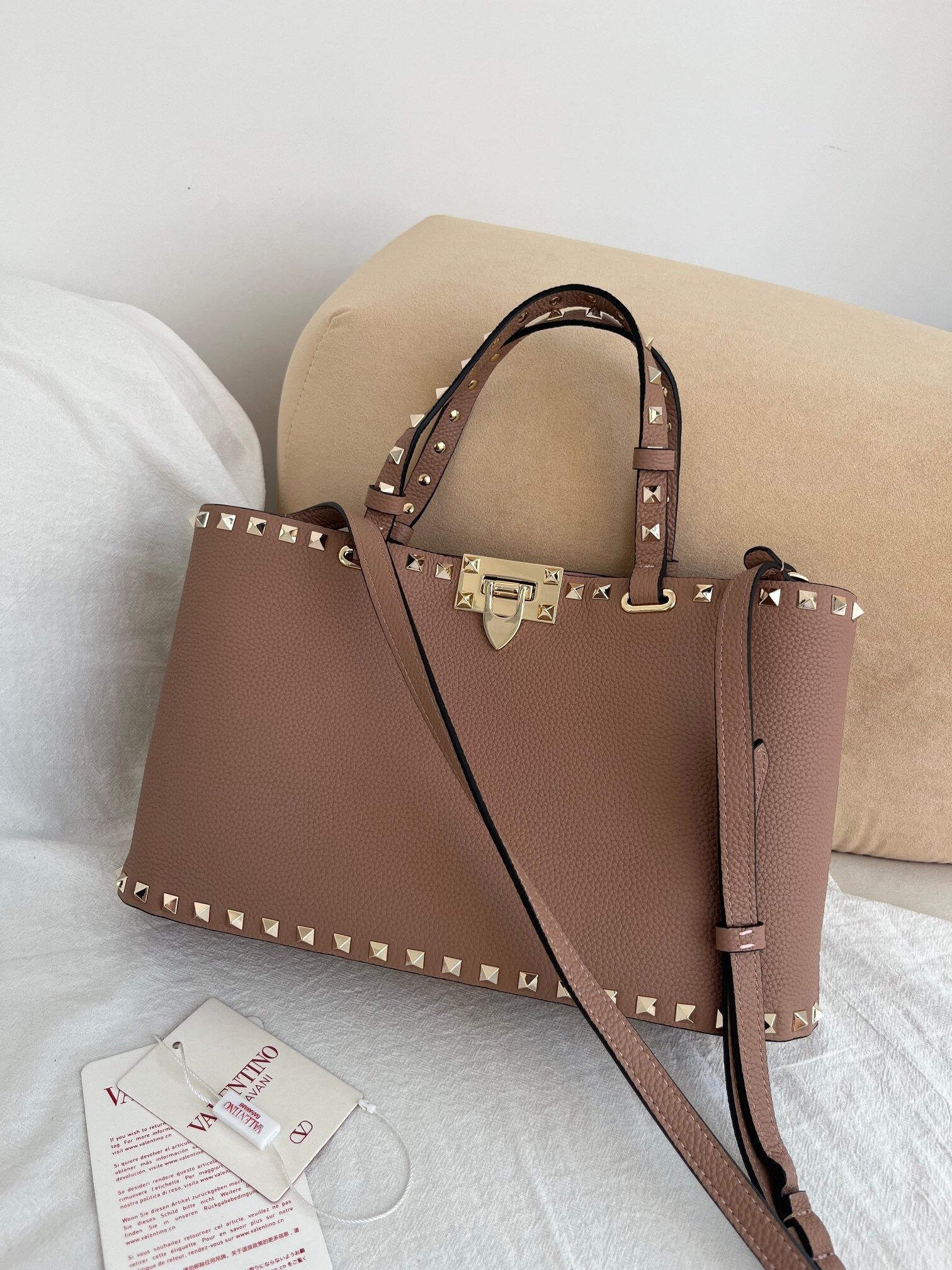 Valentino Garavani Rockstud mini top handle bag in grainy calfskin and the color is likely beige or saddle brown