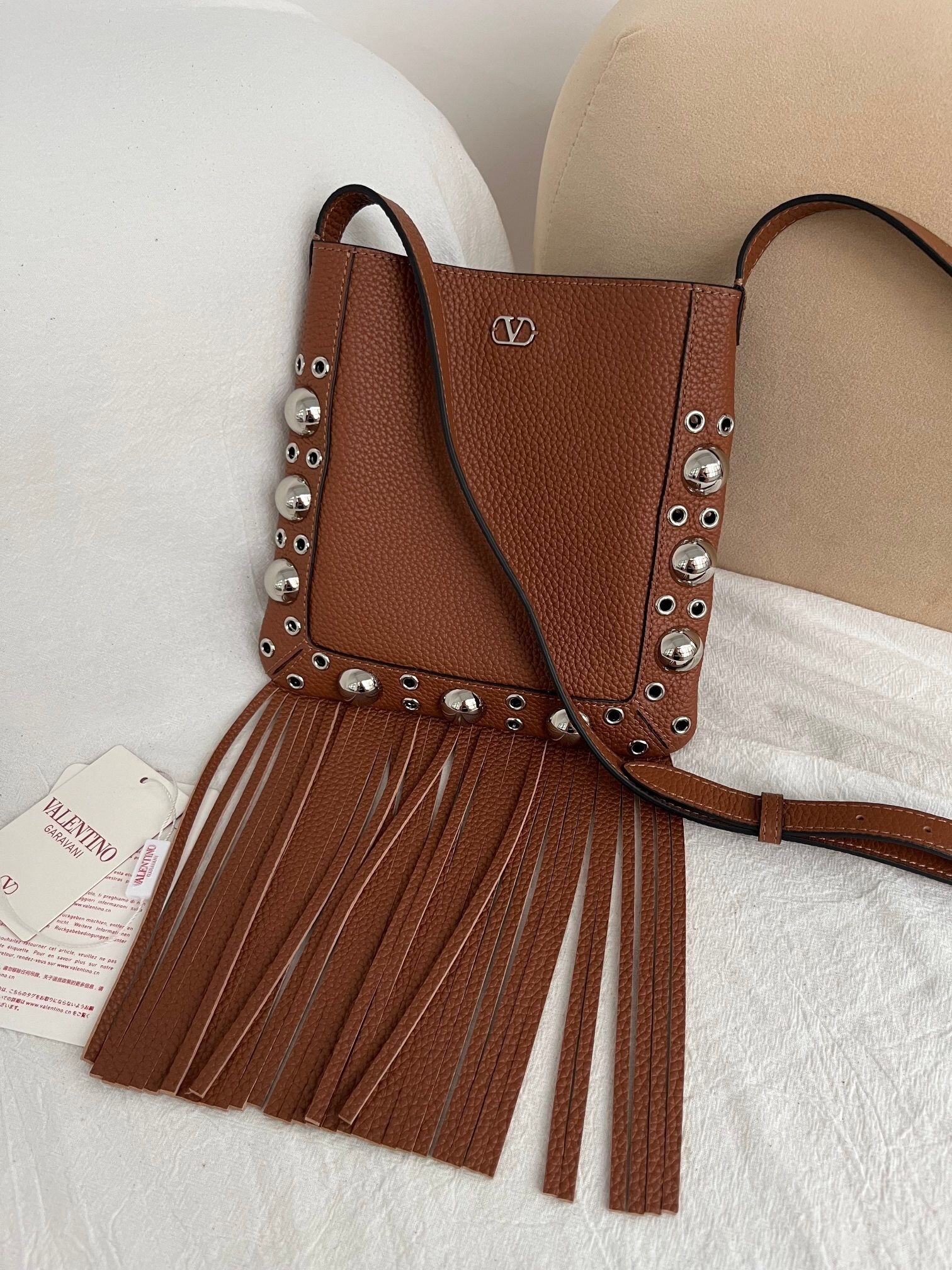 Valentino Garavani Nellcôte small shoulder bag in cedar brown grainy calfskin with fringes and ball studs