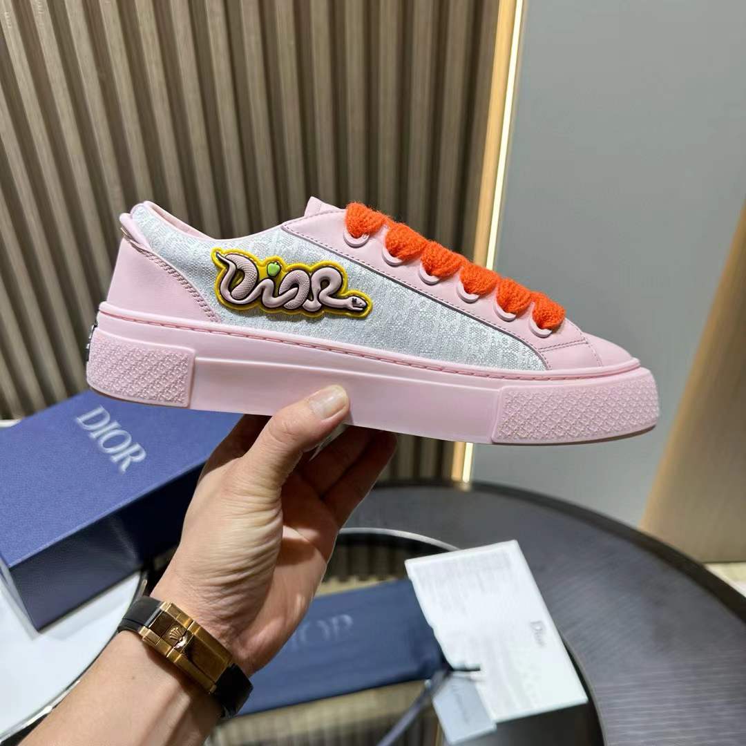 Dior x KAWS B33 low-top sneaker in a pink and grey colorway with vibrant orange laces