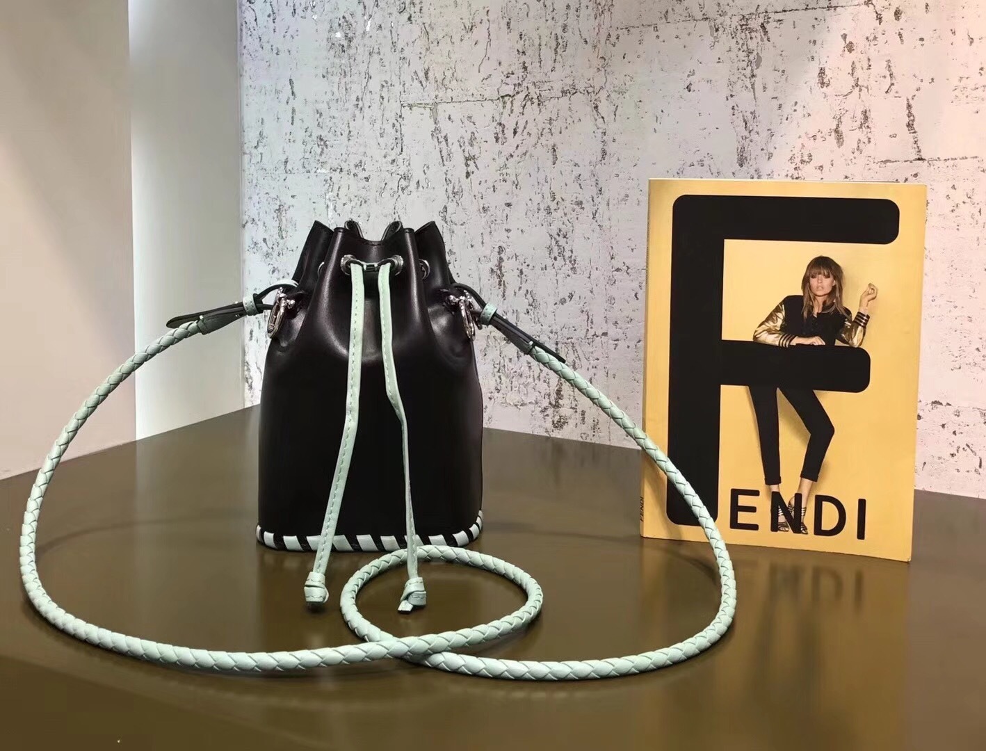Fendi Mon Tresor mini bucket bag in black leather with contrast white stitching and a light blue braided strap