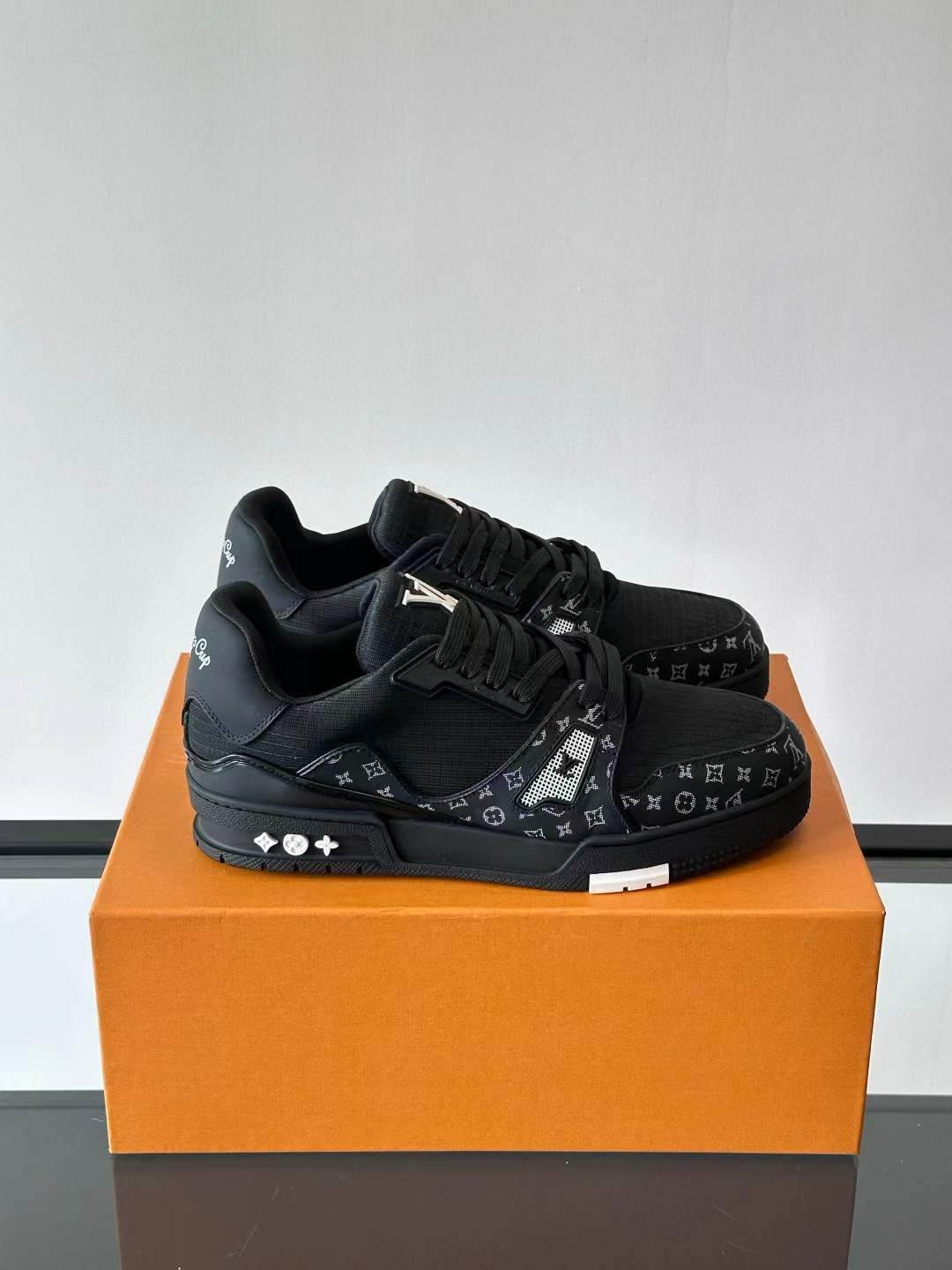 LV Trainer sneakers in a black colorway Monogram pattern on the denim and leather panels and a crystal-encrusted "LV" logo detail
