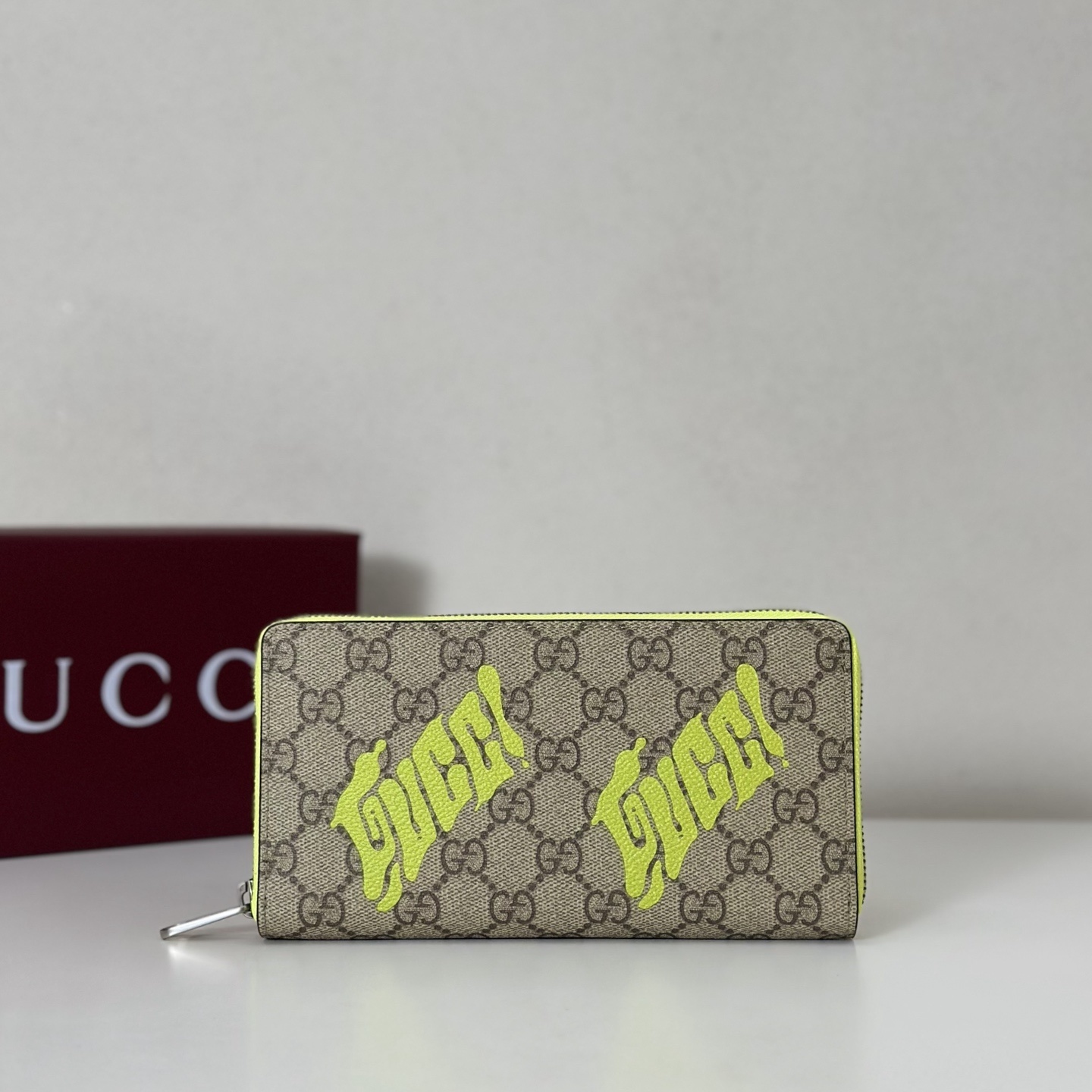 Gucci GG Supreme canvas zip-around wallet with neon yellow "Gucci" script print