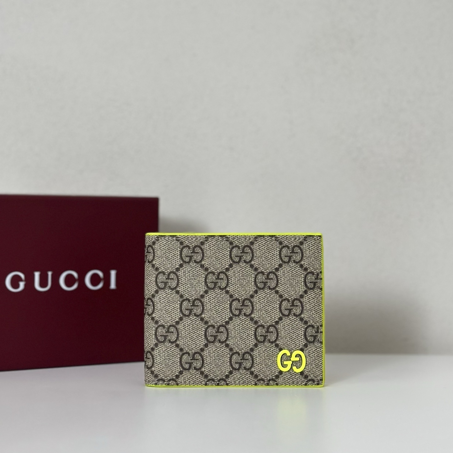 Gucci GG Canvas bifold wallet with a neon yellow trim and logo