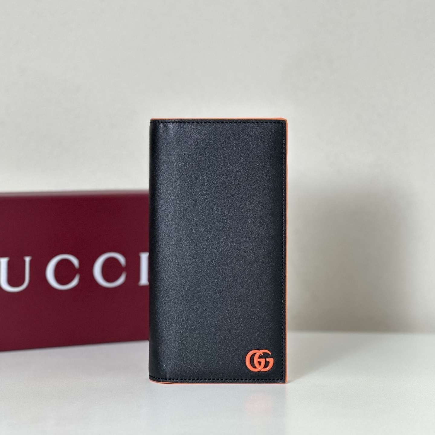 Gucci GG Marmont black leather long wallet with orange trim and the signature interlocking G logo