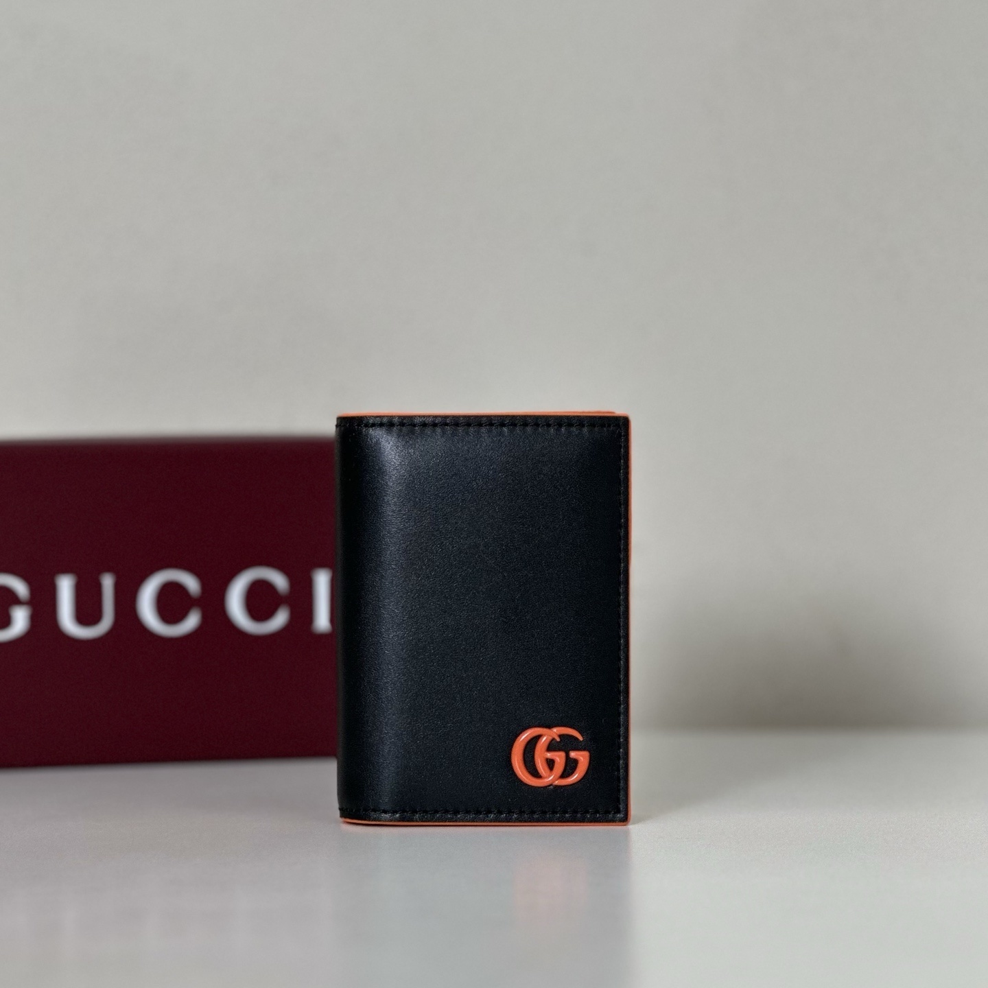Gucci GG Marmont bi-fold wallet in black leather with an orange logo and trim