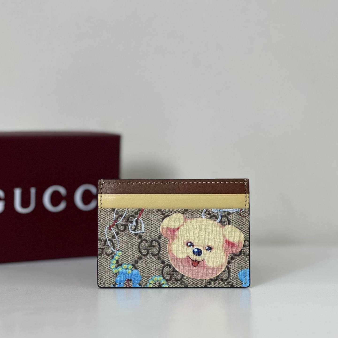 Gucci Kai Collaboration card case in GG Supreme canvas with a yellow leather accent