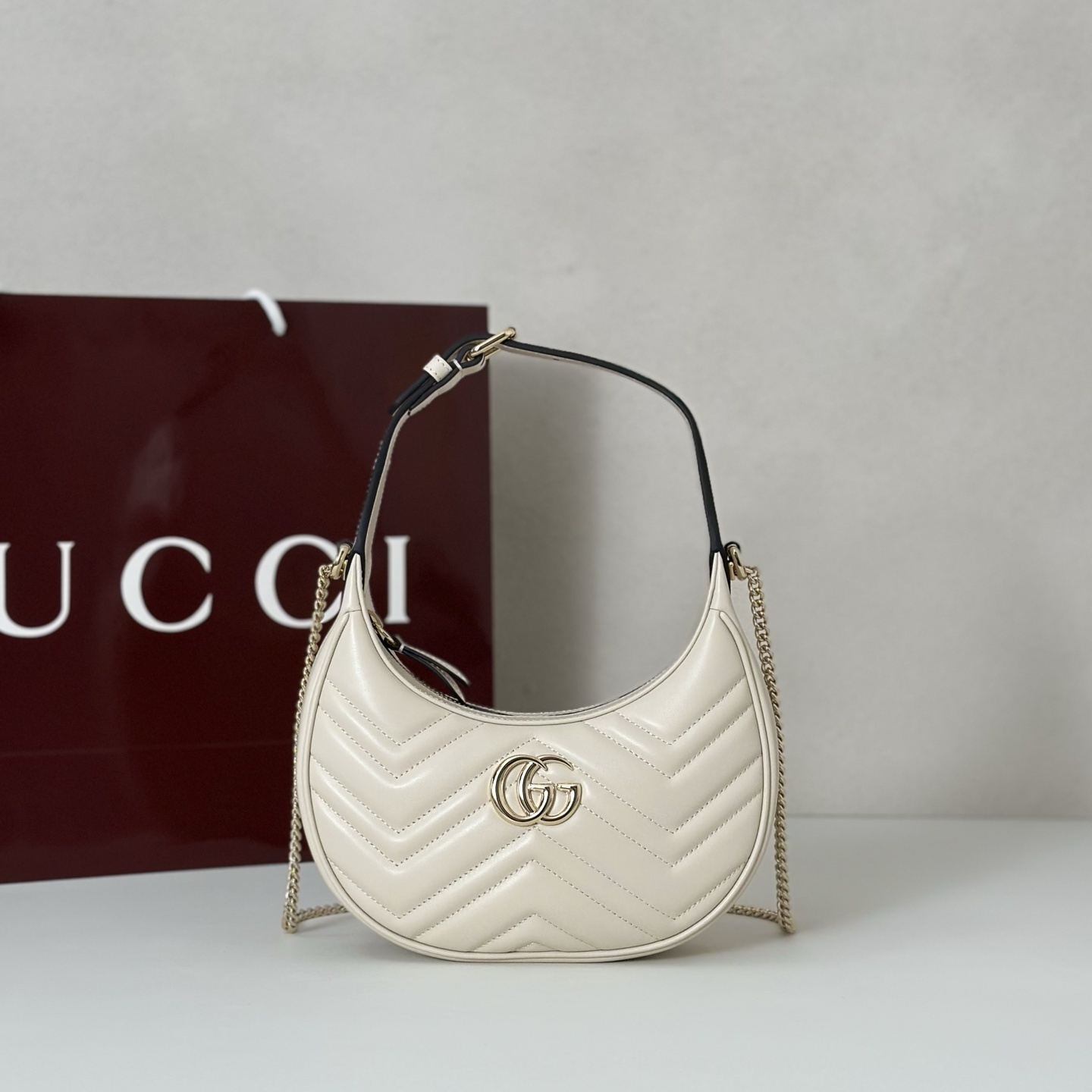 Gucci GG Marmont Half-Moon Shaped Mini bag in white matelassé leather with antique gold-toned hardware
