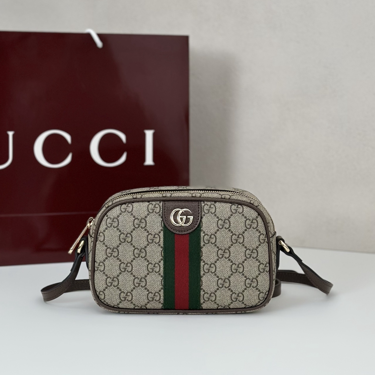 Gucci Ophidia Small camera bag in beige and dark brown GG Supreme canvas with brown leather trim, a dark blue and red Web stripe, and gold-toned Double G hardware