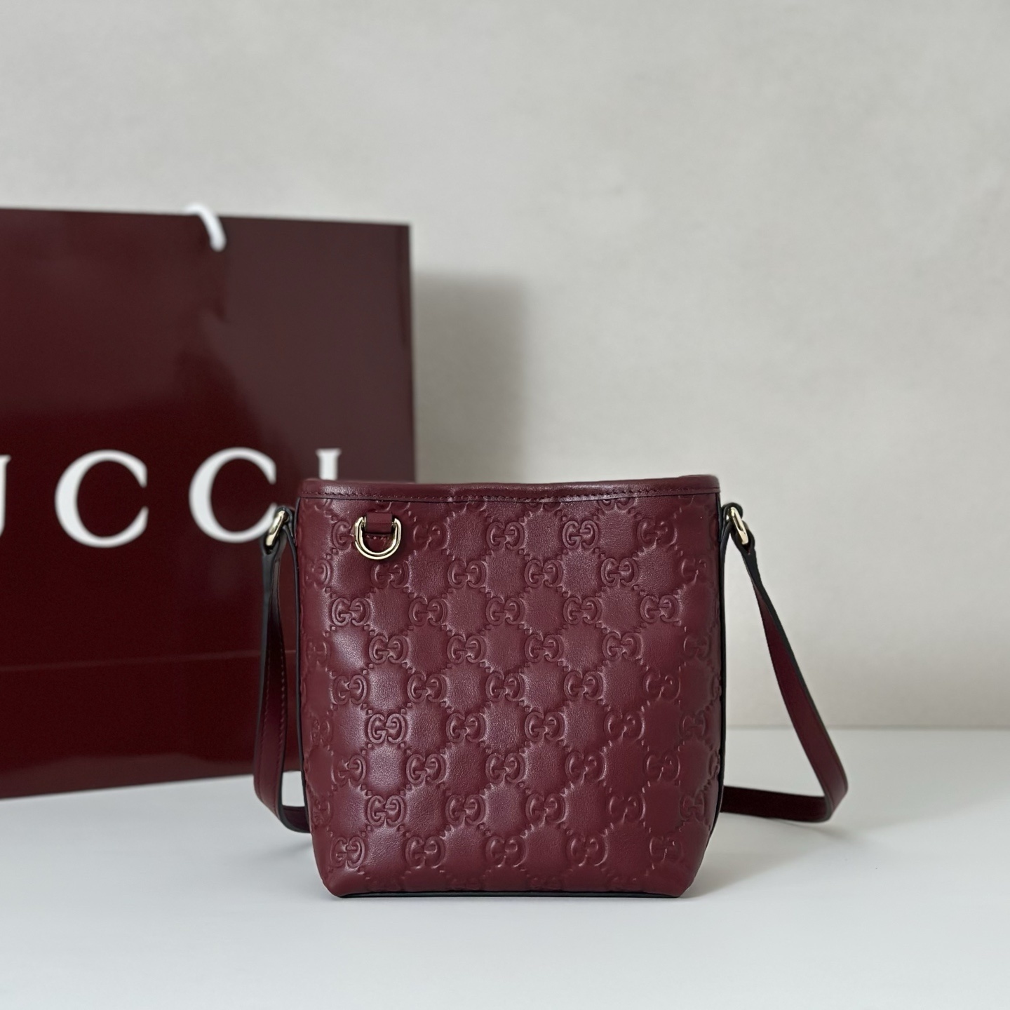 Gucci GG Emblem debossed leather bucket bag in a burgundy or "Rosso Ancora" red color