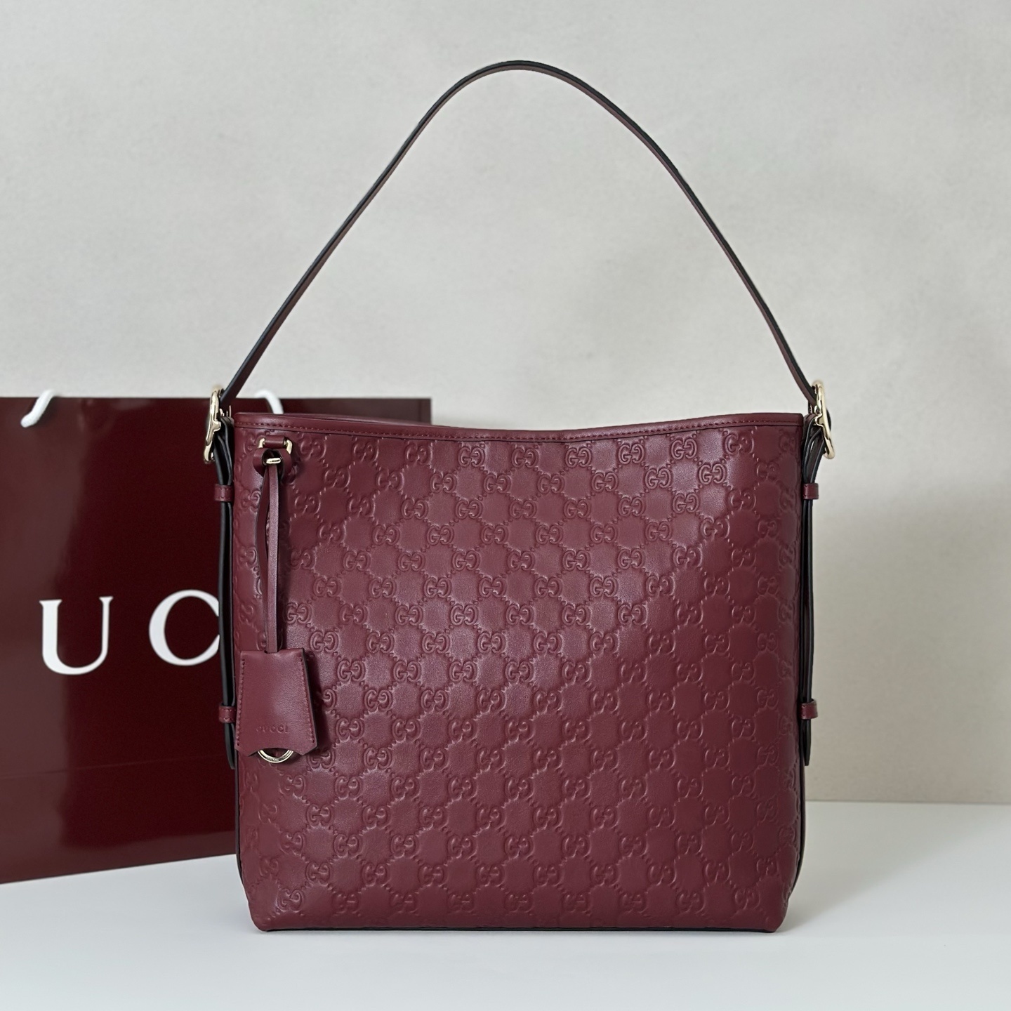 Gucci GG Emblem medium shoulder bag in a red or burgundy color GG embossed leather.