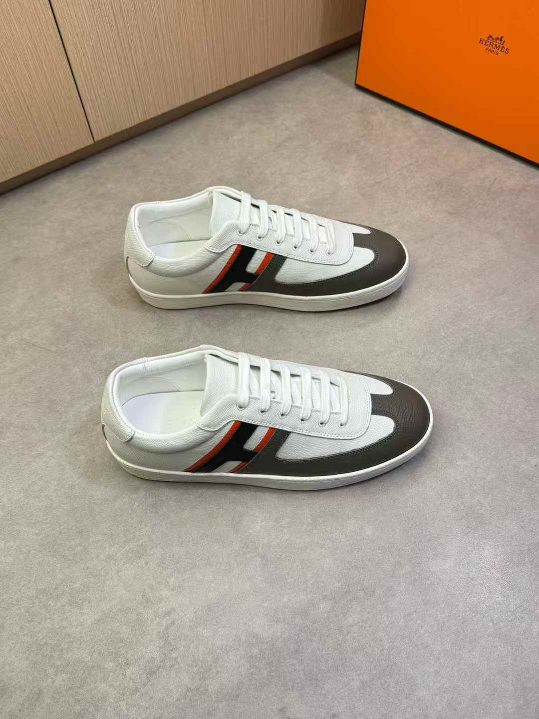 Hermès Boomerang sneakers in white calfskin and suede with a black and red "H" detail and an orange rubber sole