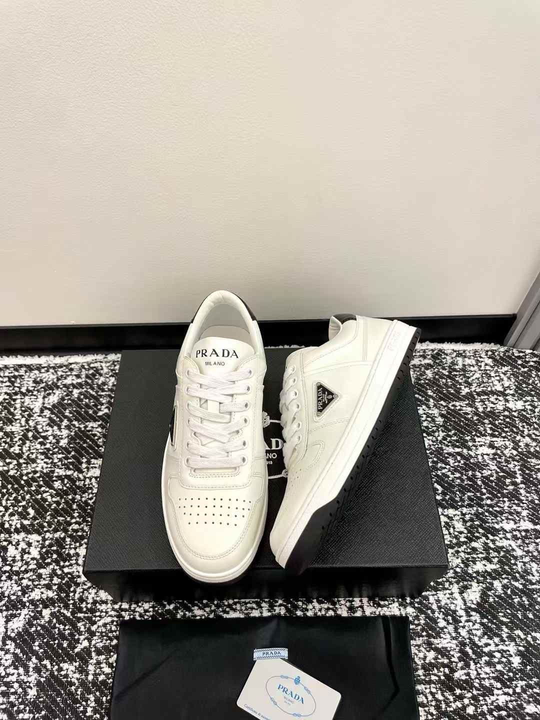 Prada Downtown perforated leather sneakers in a white and black colorway