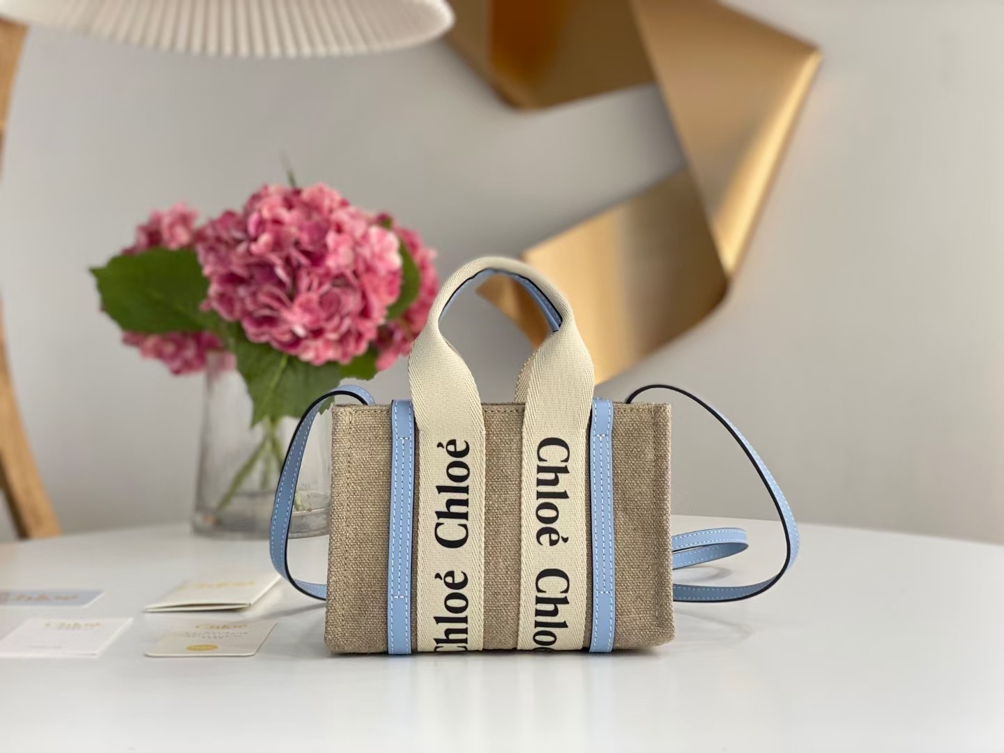 Chloe Woody mini tote bag inen canvas and shiny calfskin with a blue logo ribbon.