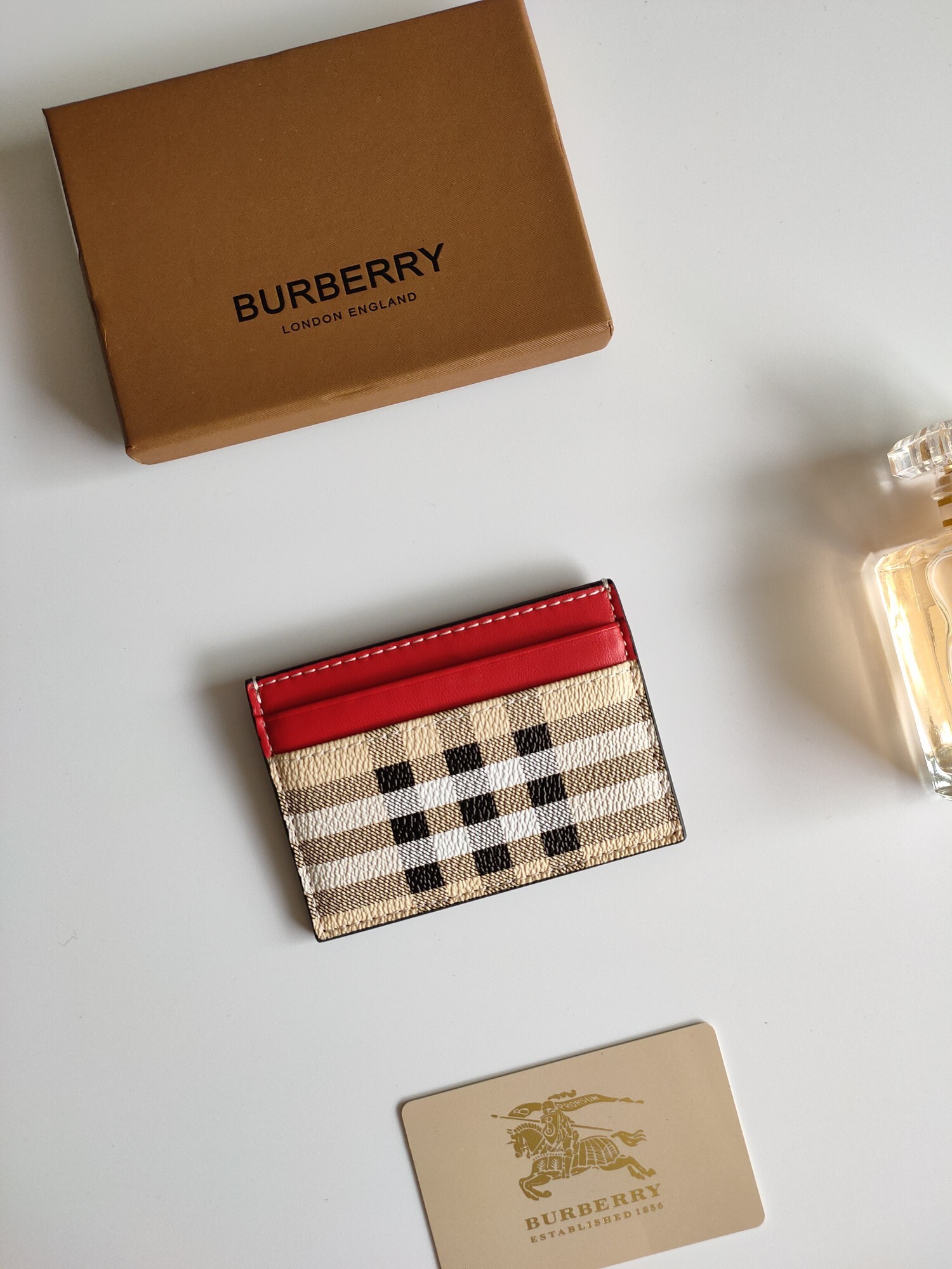 Burberry card holder featuring the brand's signature check pattern and red leather trim