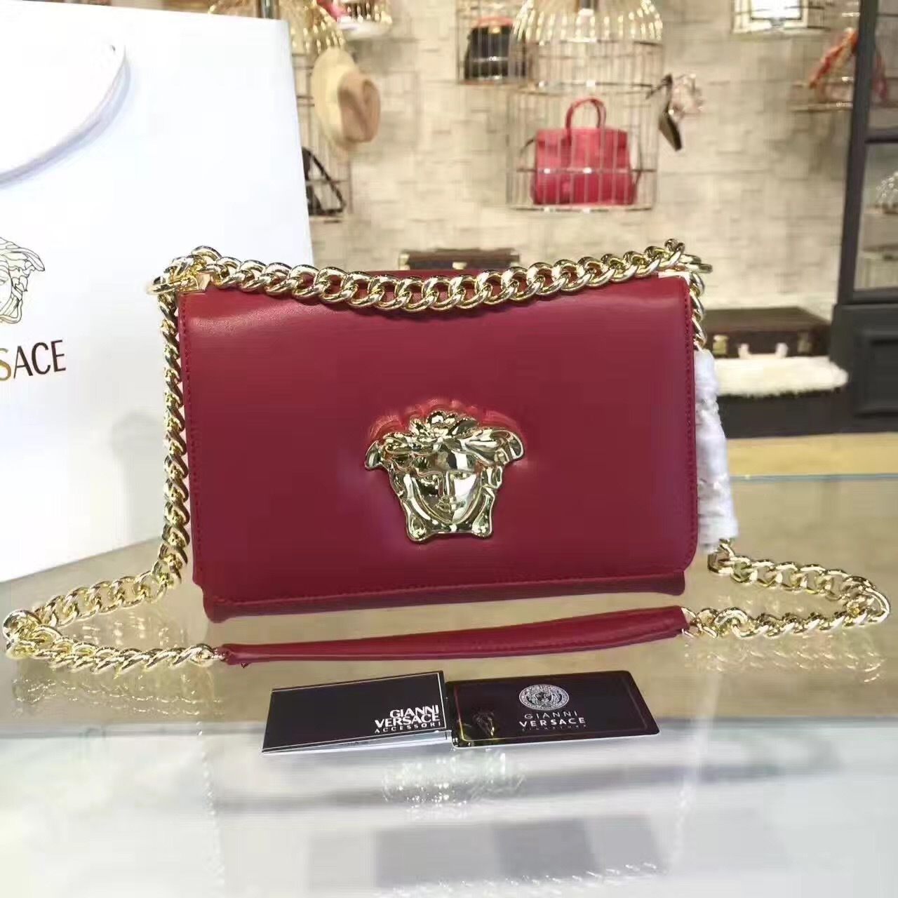 Versace La Medusa small leather crossbody bag in a dark red or fuchsia color with a gold-tone chain strap