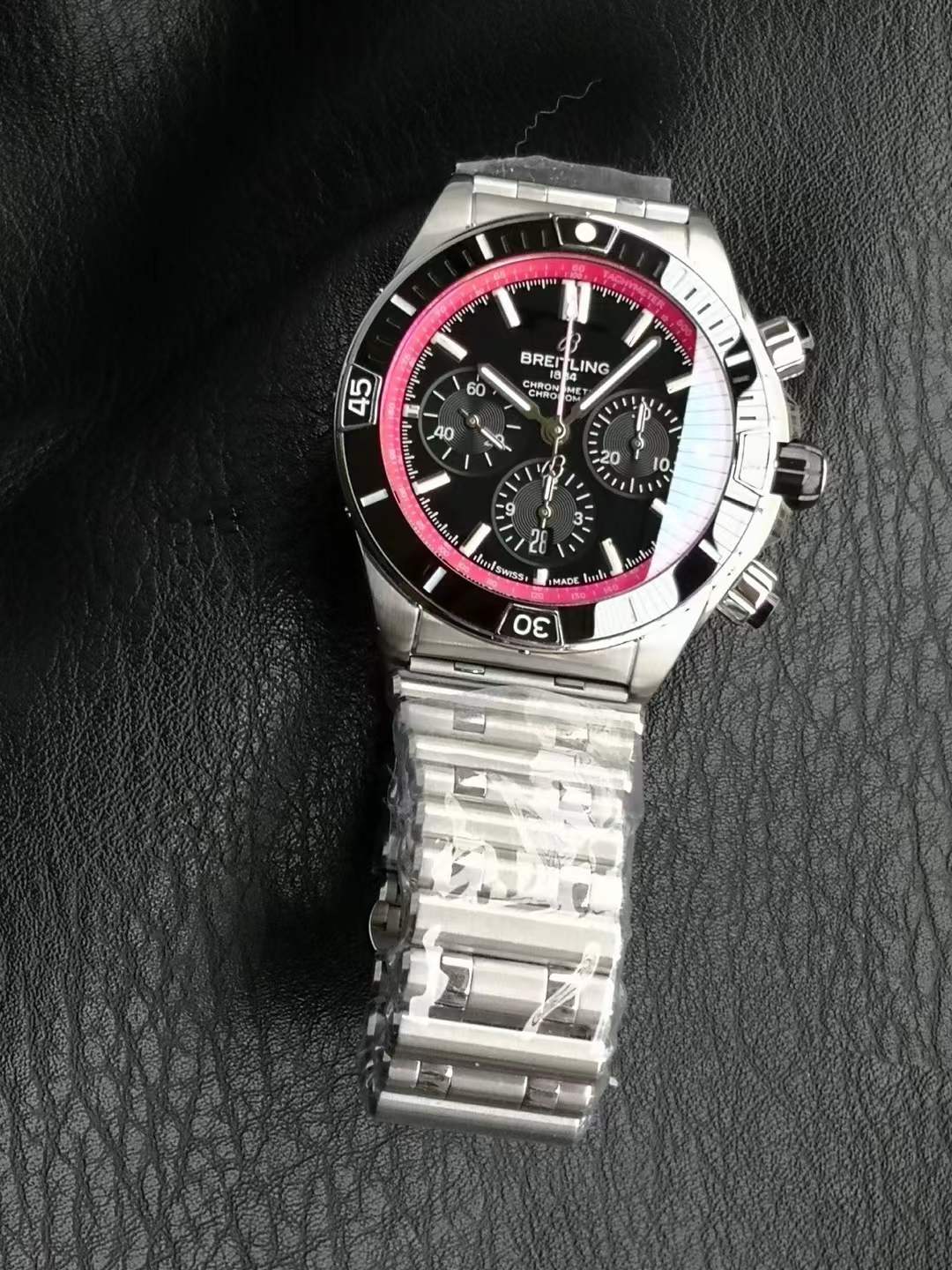 Breitling Super Chronomat B01 44 in stainless steel with a black dial, black ceramic bezel, and a Rouleaux-style metal bracelet.