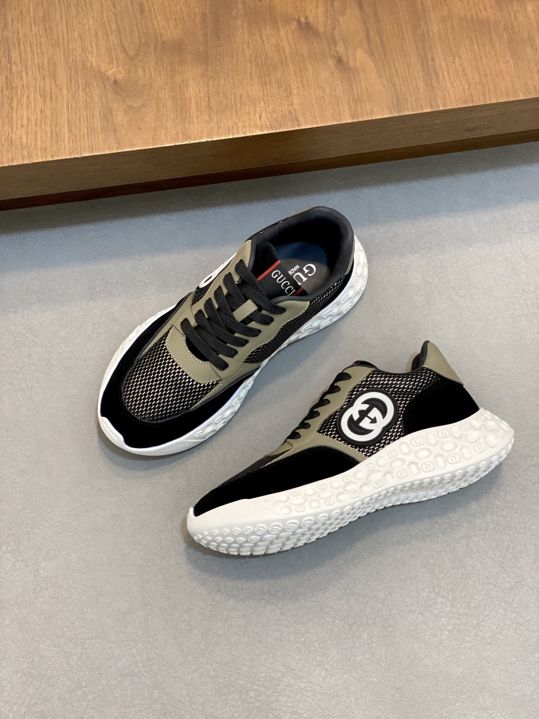 Gucci black and beige sneakers featuring the interlocking G logo on the side.
