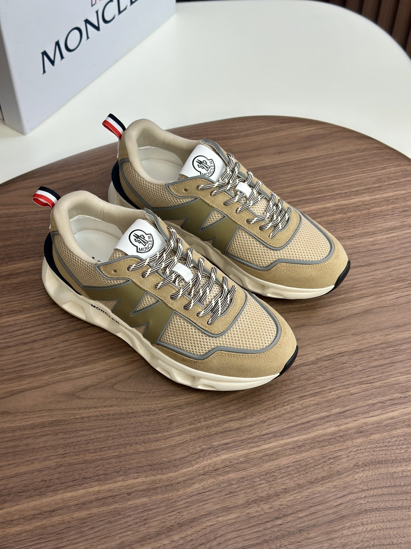 Moncler Pacey sneakers in a beige/neutral colorway with a red, white, and navy striped heel tab.