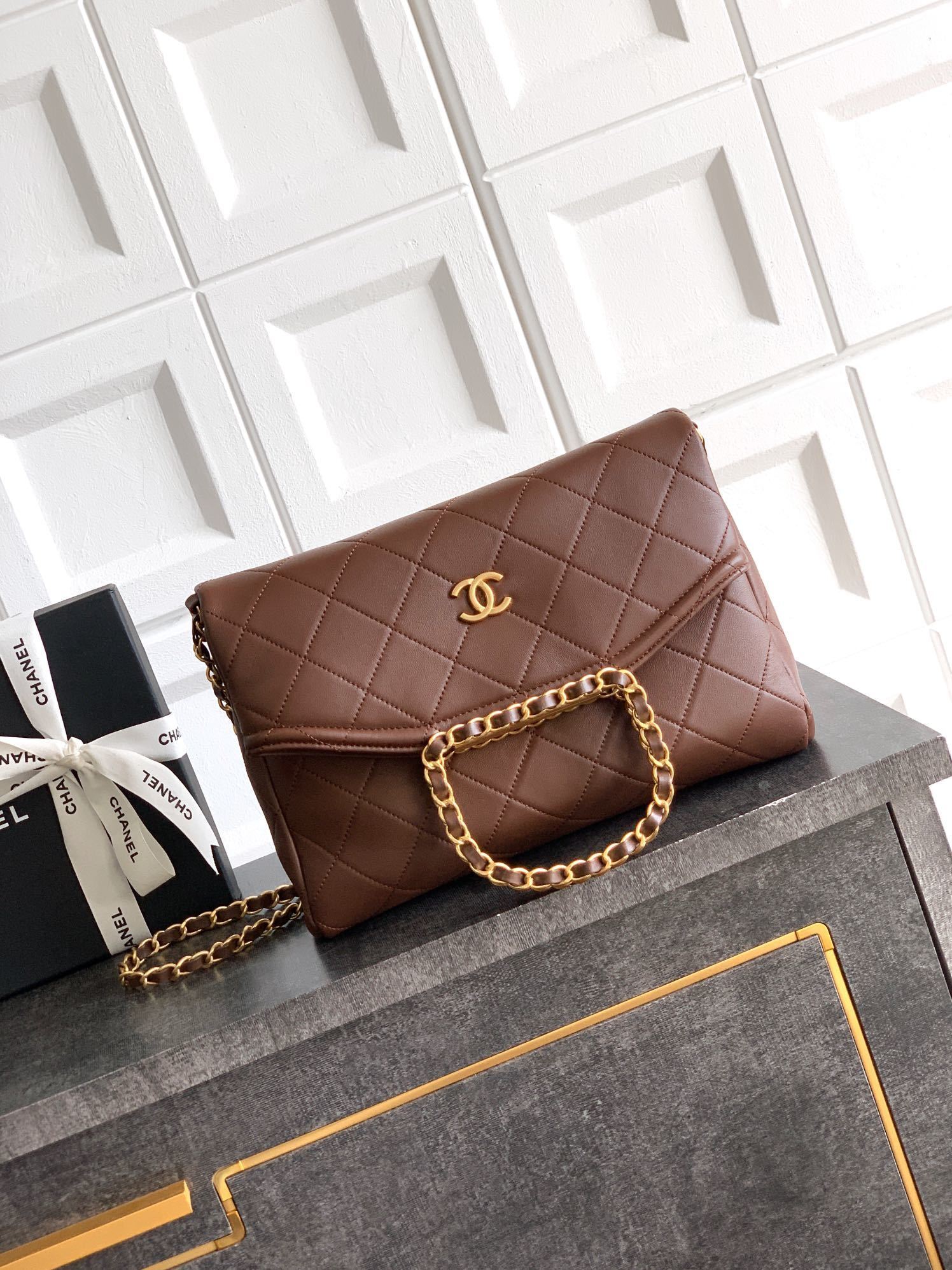 Chanel flap bag brown with a top handle and gold-tone hardware.
