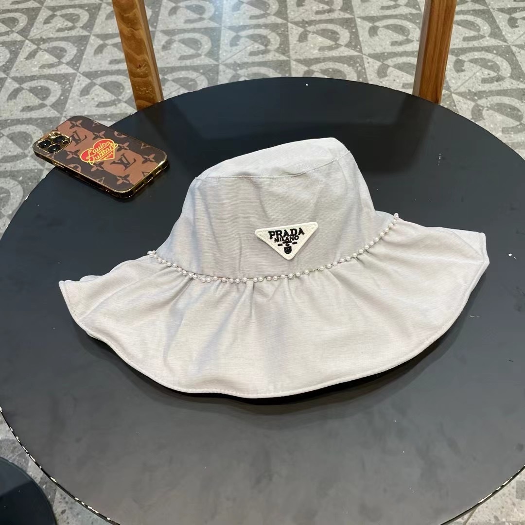 Prada Re-Nylon bucket hat featuring a ruffled brim with pearl trim and the iconic enameled metal triangle logo