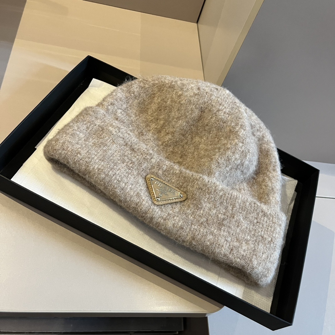 Prada wool and cashmere blend beanie with the iconic enameled metal triangle logo in a brown or camel color