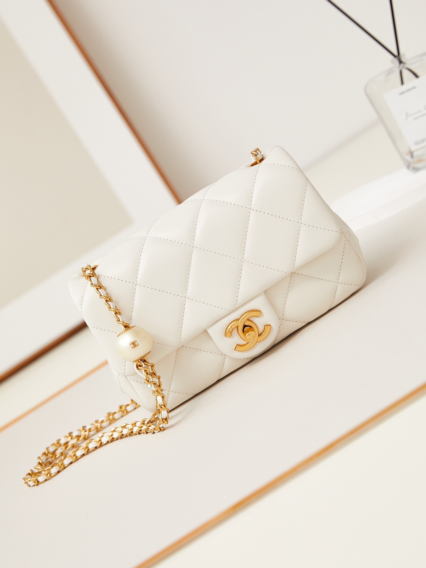 Chanel mini flap bag in white quilted lambskin leather with a pearl and gold-tone chain strap