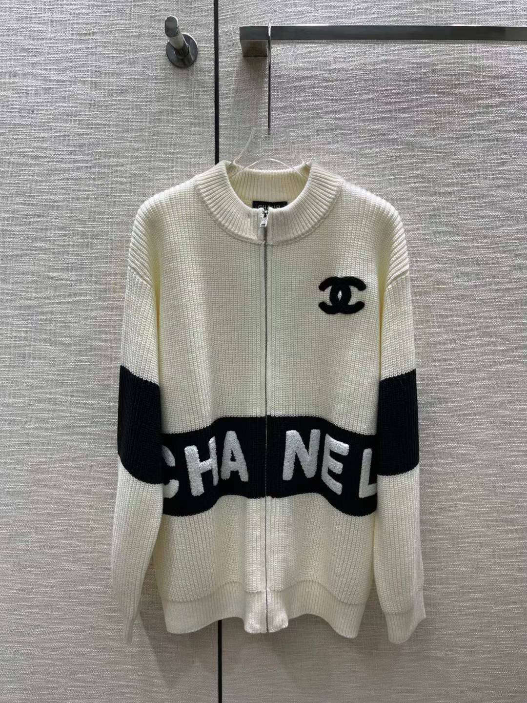 Chanel zip-up cardigan in white and black with a logo on the chest and the brand name across the front