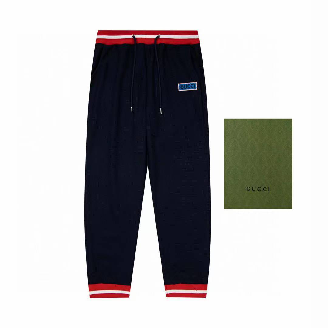 Gucci men's navy blue joggers with red and white striped cuffs and waistband.