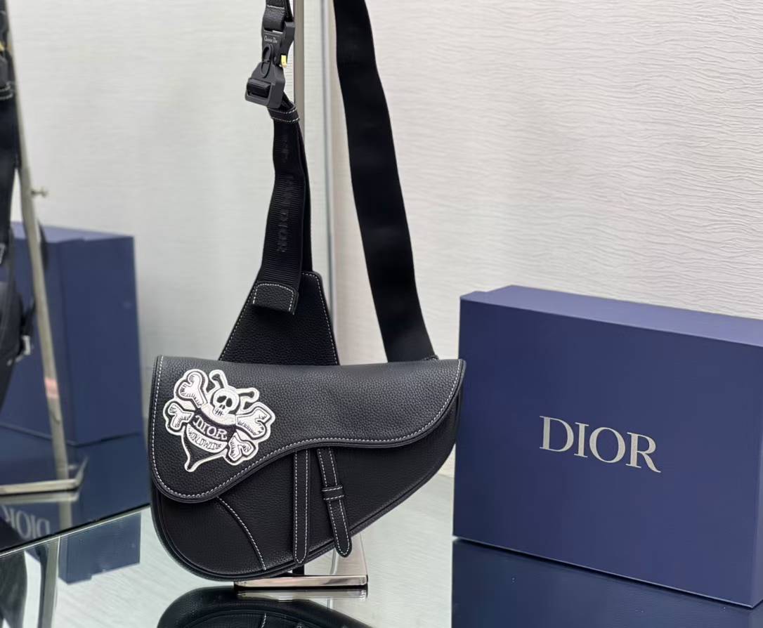 Dior x Shawn Stussy Saddle Bag in black grained calfskin leather with a skull and crossbones graphic