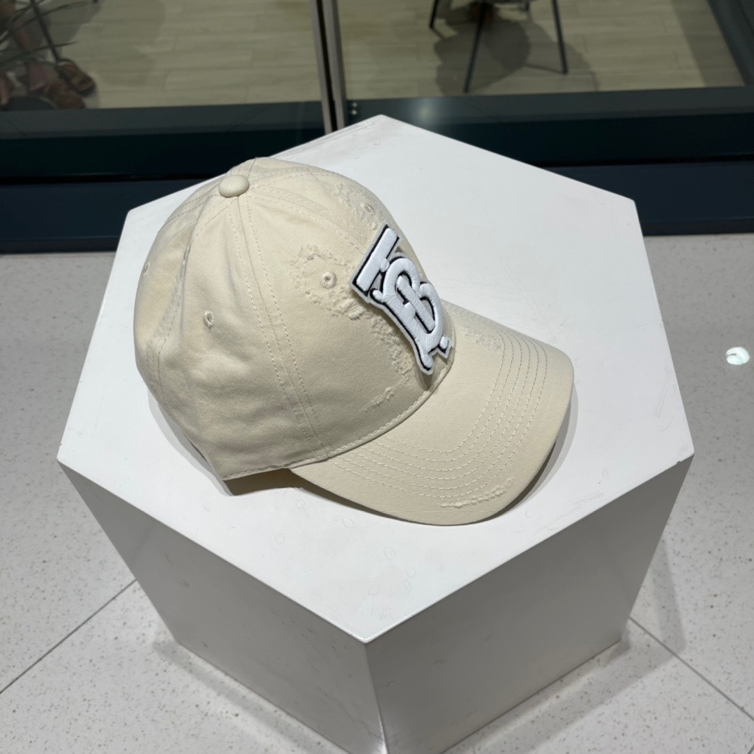 Burberry cotton gabardine baseball cap in a light beige or tan color with a white and black embroidered Thomas Burberry monogram logo.
